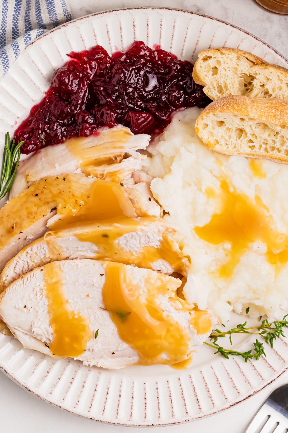 plate loaded with turkey, potatoes, cranberry, and bread