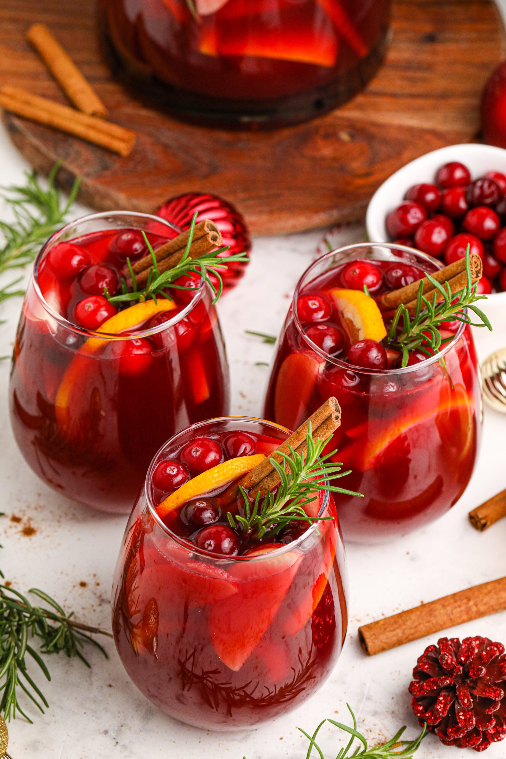 three glasses of Cranberry Apple Christmas Sangria with fresh cranberries and cinnamon sticks in the glasses