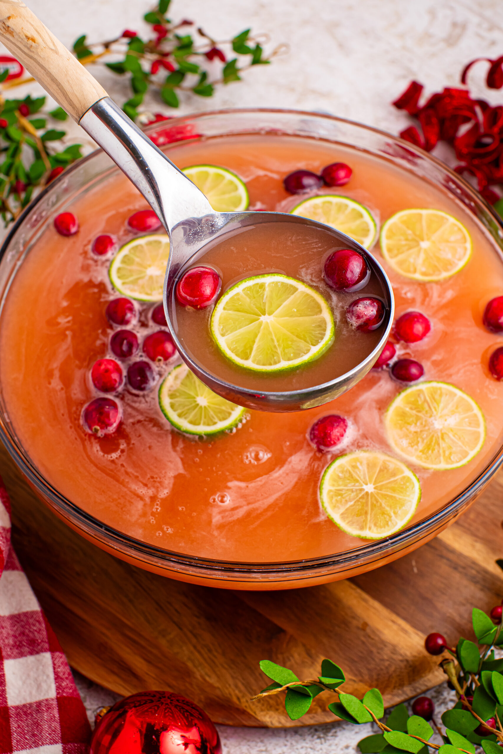 Santas giggle juice in a large punch bowl with a serving spoon lifting a cup