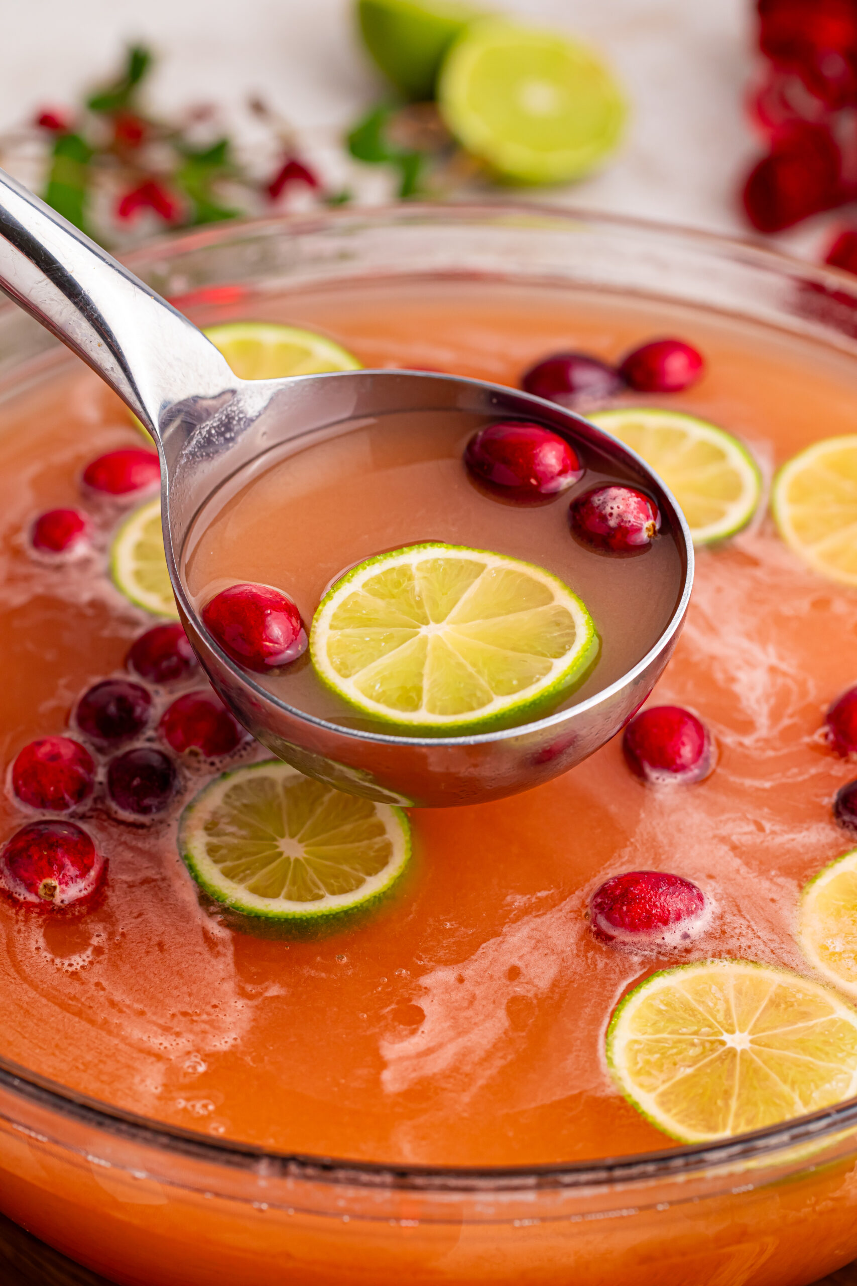 Giggle juice in a punch bowl with sliced limes and cranberries
