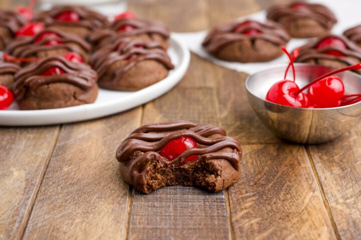 Chocolate Cherry Cookie on a wooden table with the front one missing a bite 