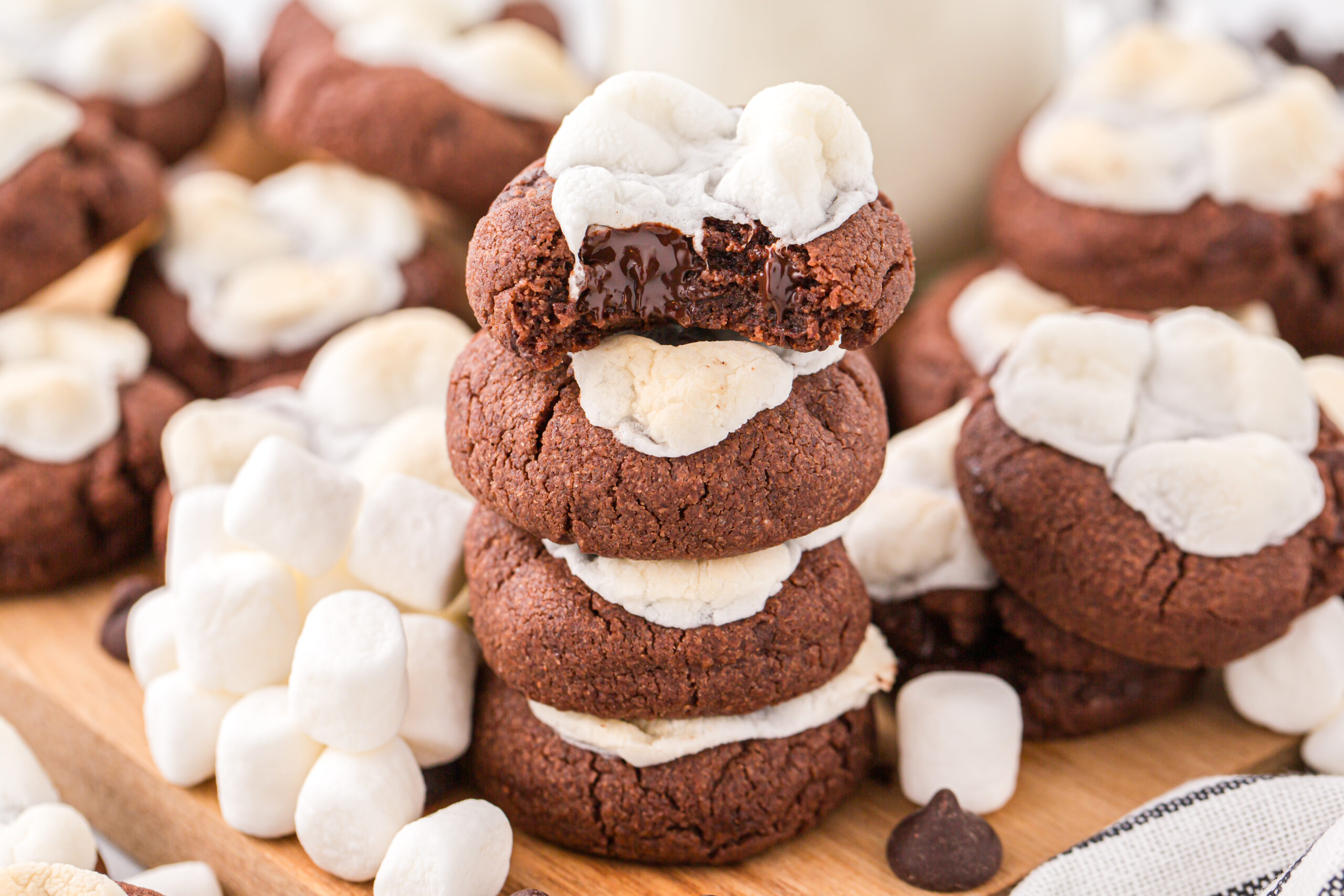 Hot chocolate cookies stacked with a bite taken out from the top cookie showing the chocolatey center