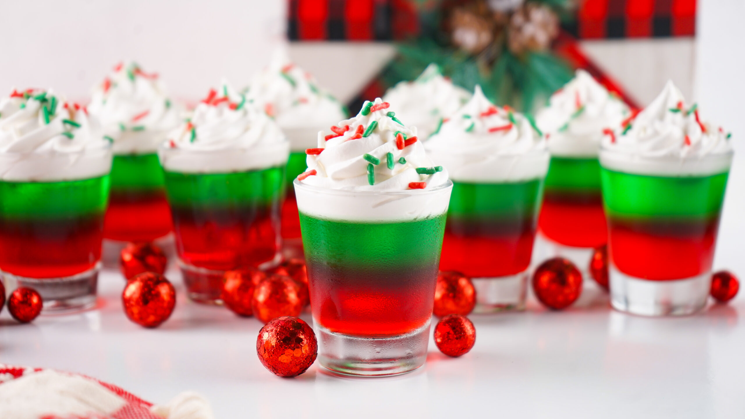 Christmas Jello Shots on a white table with red ornaments around them