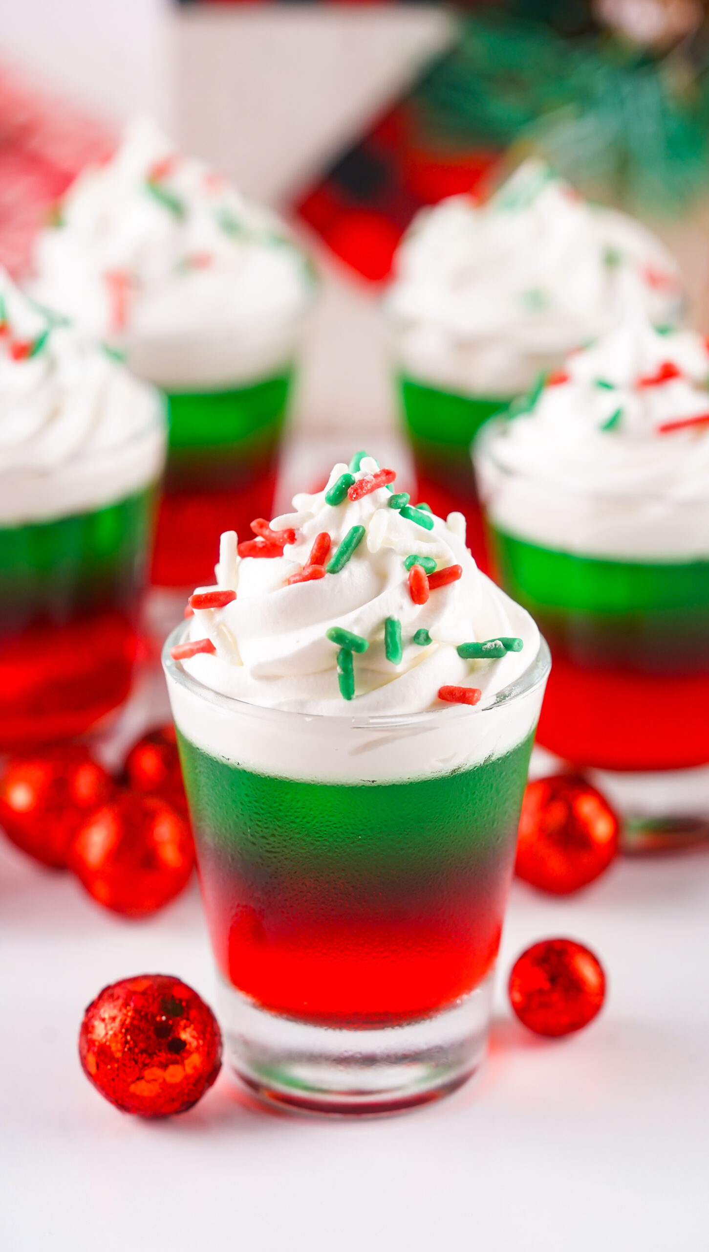 Christmas Jello Shots on a white able with red ornaments around them