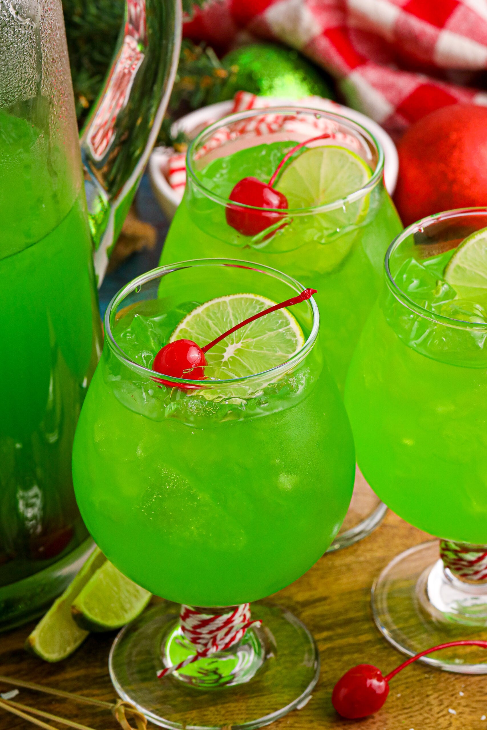 Grinch Punch in a clear glass on a table with a cherry and a lime slice in the glasses