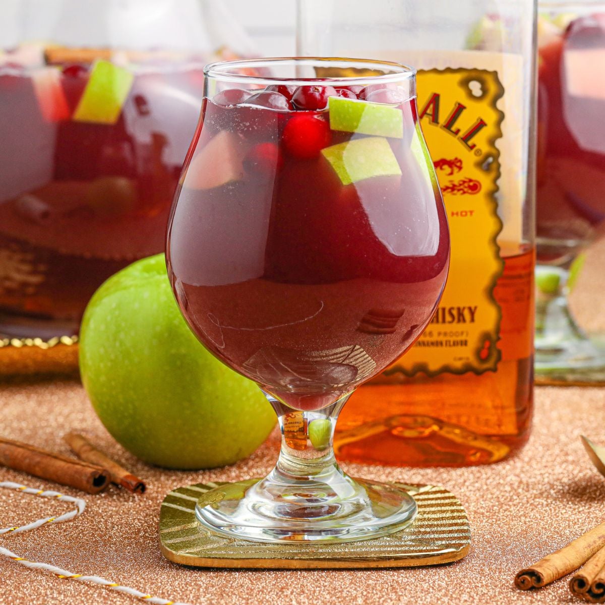 Fireball Sangria in glasses with whiskey bottle and apple behind it