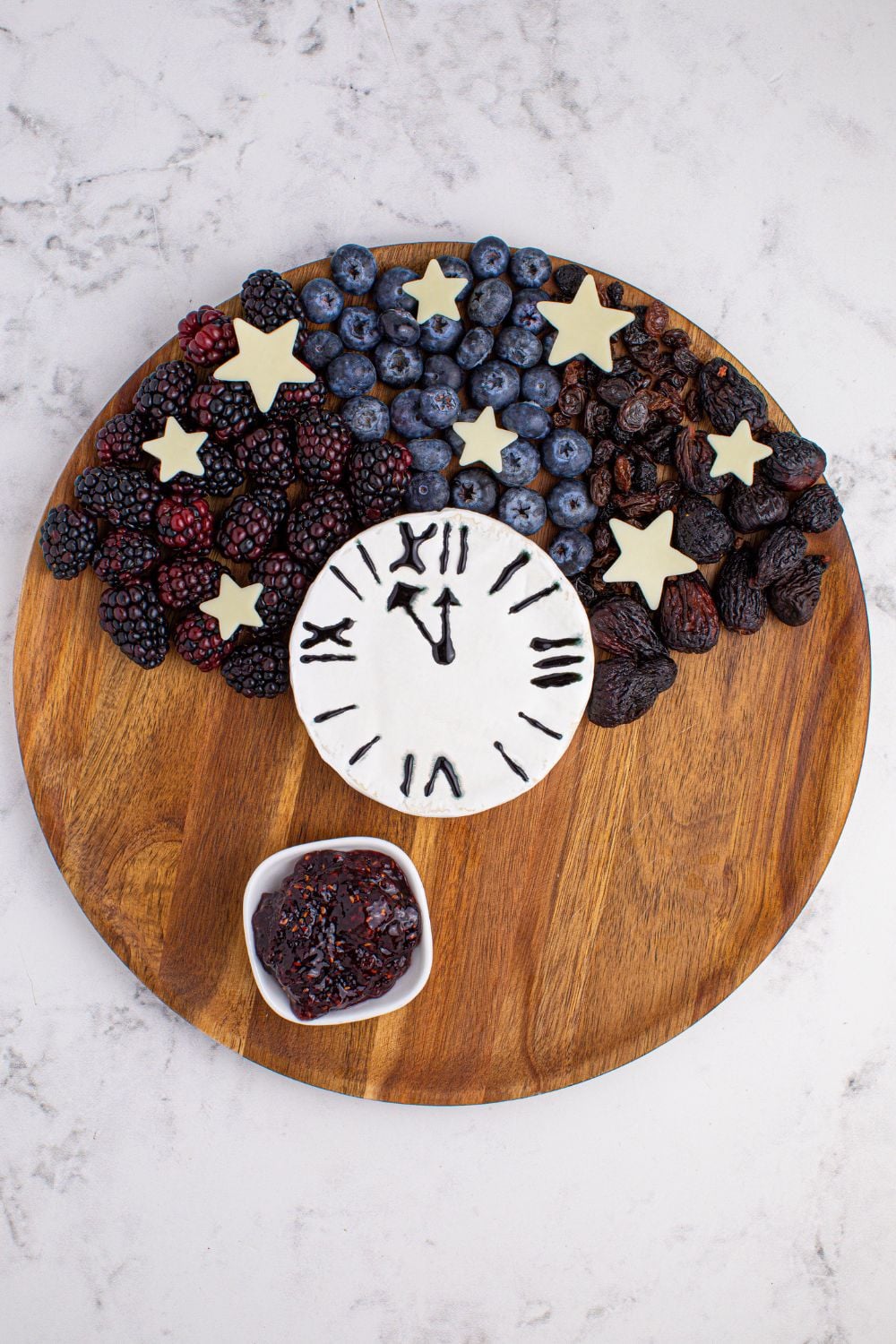 berries and a brie block on a round cutting board showing how to assemble a charcuterie board 