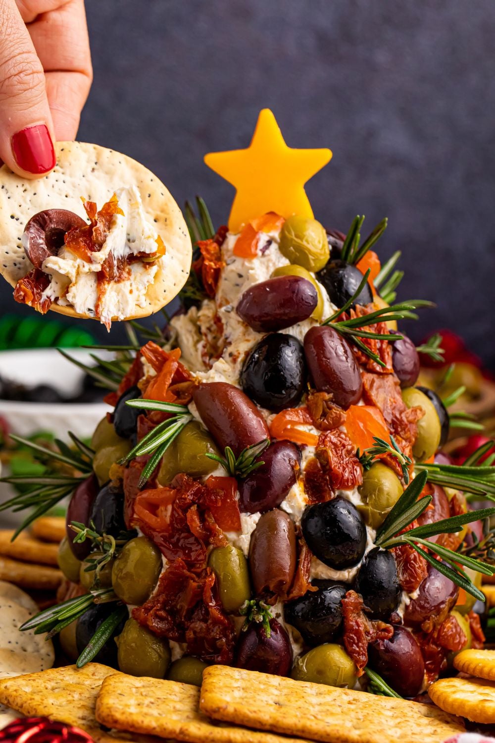 cracker with cheeseball on it and some olives