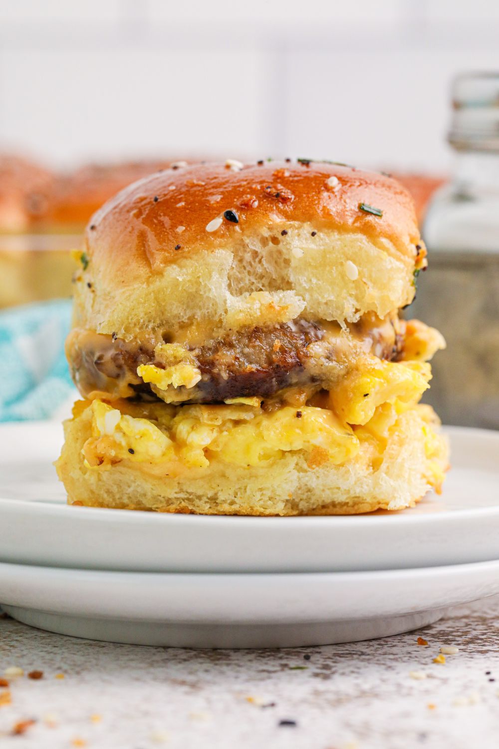 two plates stacked on top of each other with one Breakfast Slider on the plate with egg, cheese and sausage 