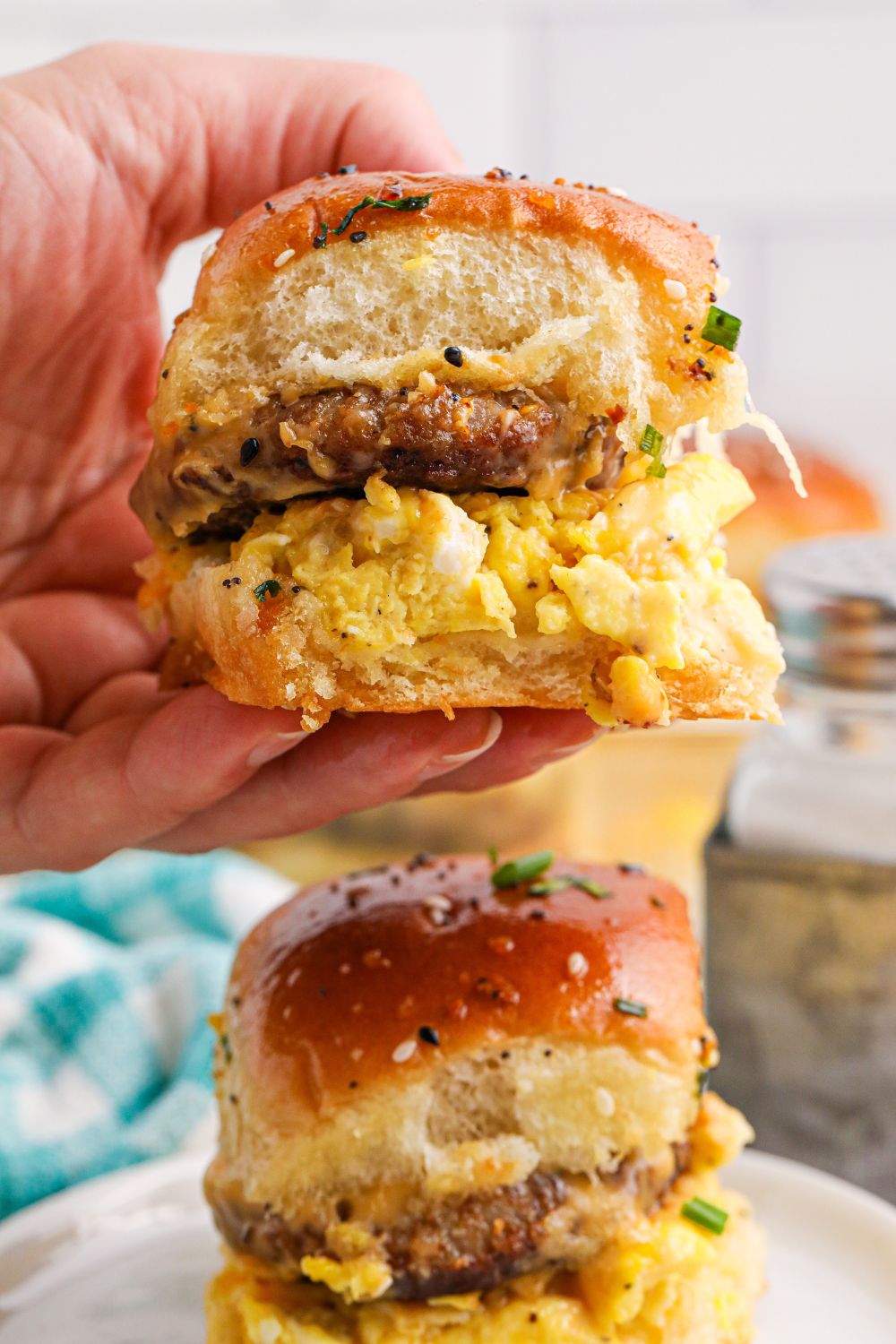 Breakfast Sliders on plate with one being held in a hand 
