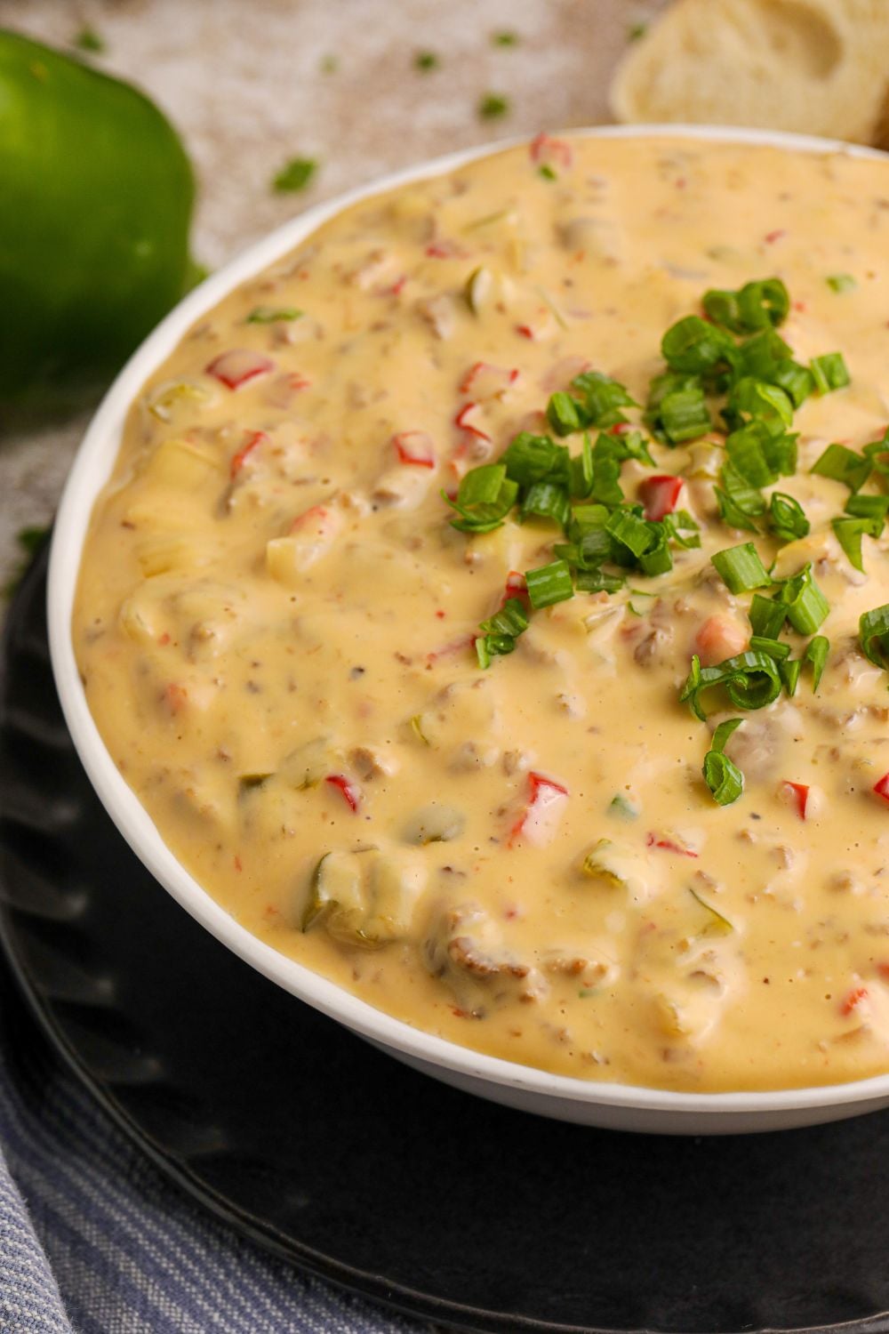 Crock Pot Philly Cheesesteak Dip in a glass bowl on the table, showing only half of the bowl on table