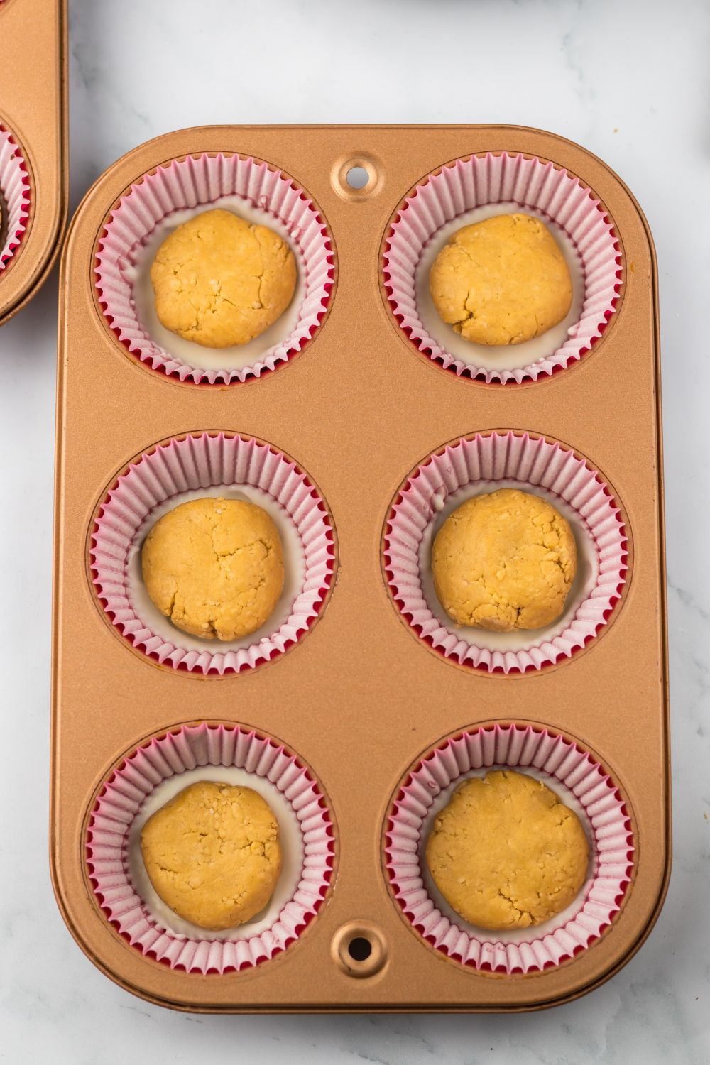 balls of peanut butter on top of chocolate in a muffin tin