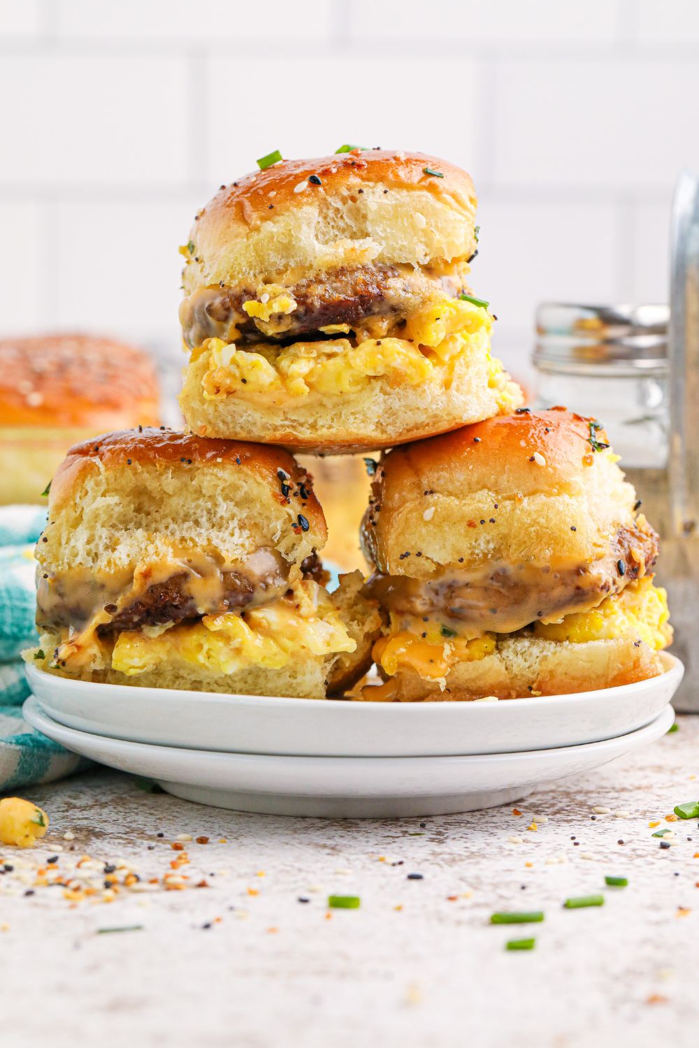 Breakfast Sliders on a plate with some fresh herbs sprinkled on table in the front 