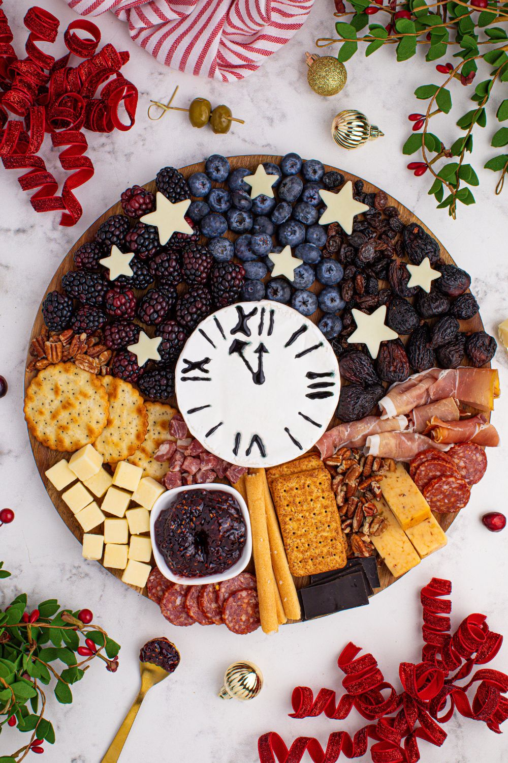 New Year's Eve Charcuterie Board on table with an overhead look with nuts, cheese, berries and more on the serving tray 
