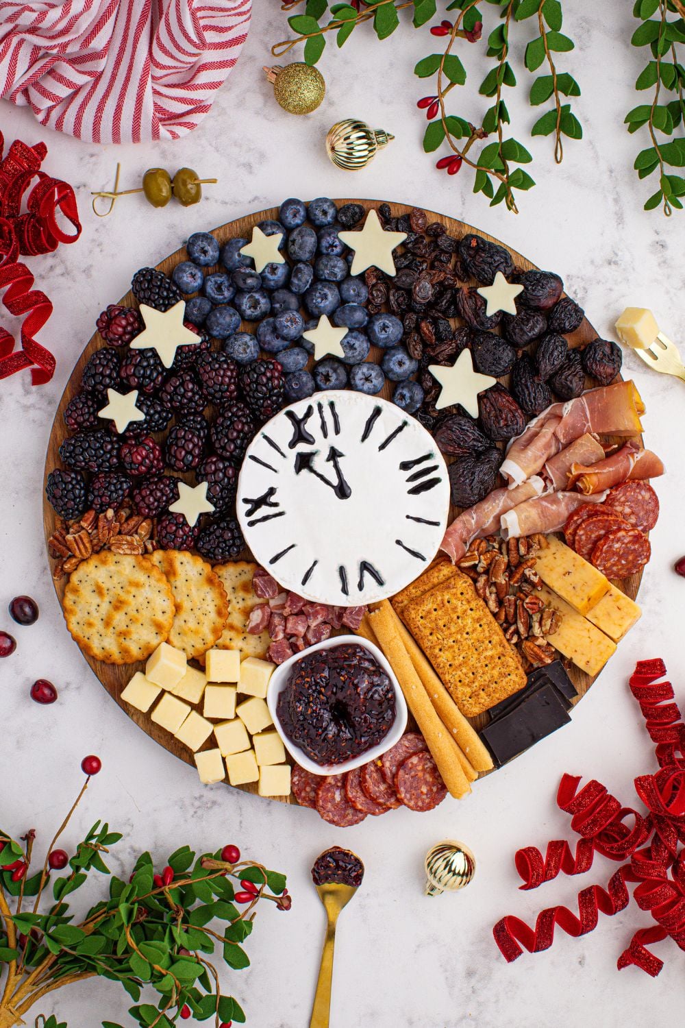 New Year's Eve Charcuterie Board with garnishes of fresh herbs, berries, and more on table 