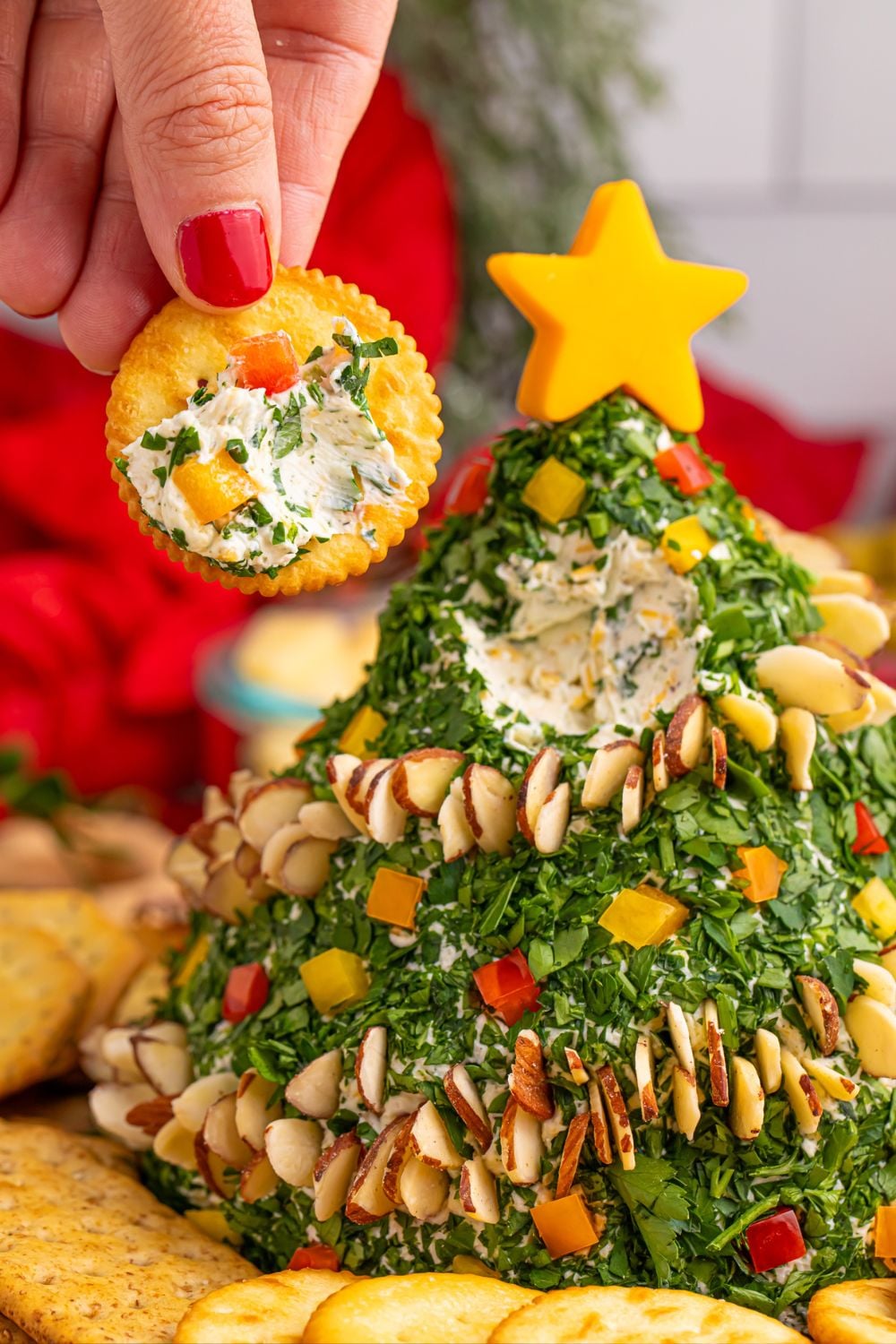 cracker with cheeseball on it being held in a hand