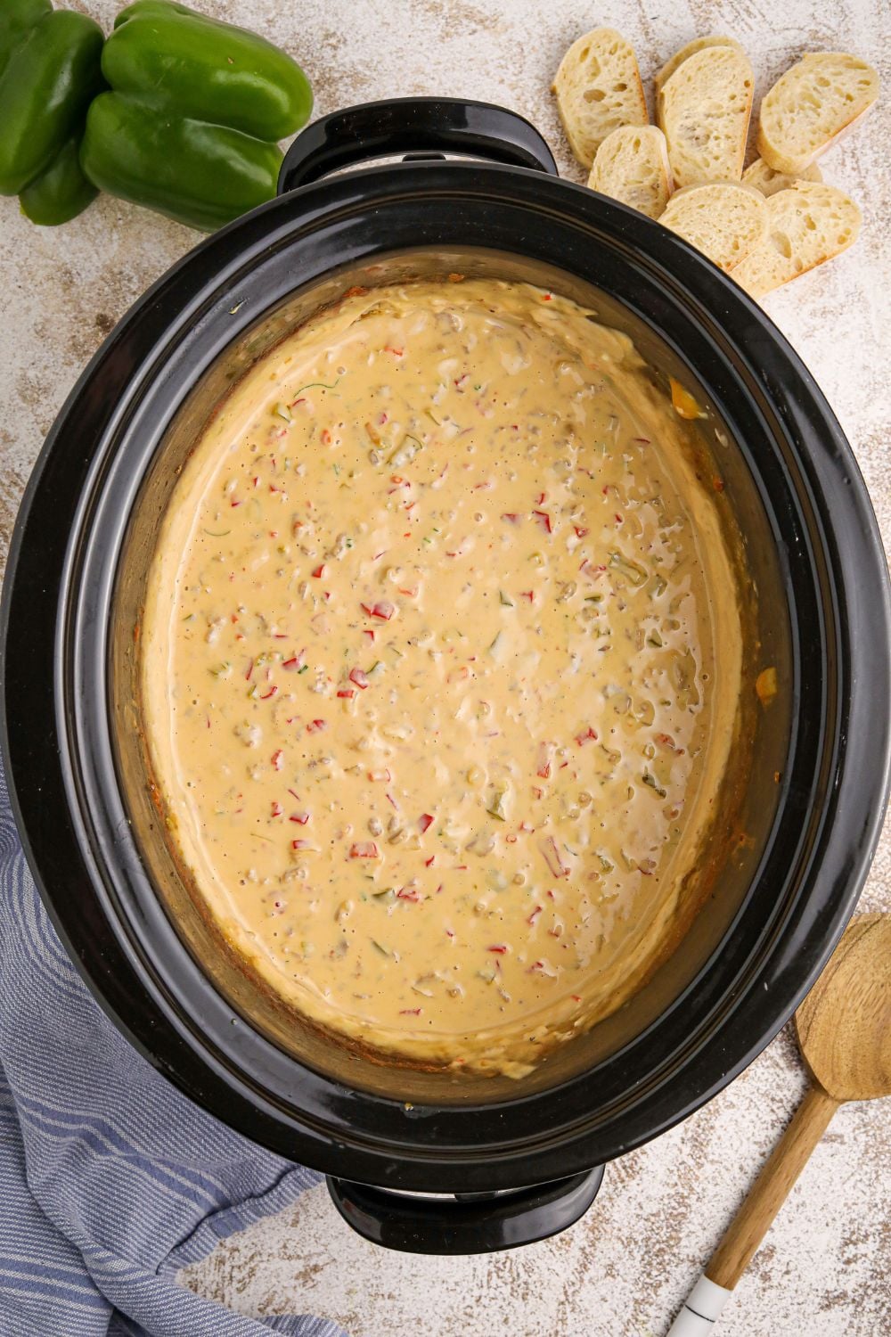 overhead look of Crock Pot Philly Cheesesteak Dip on table with a wooden spatula on the side