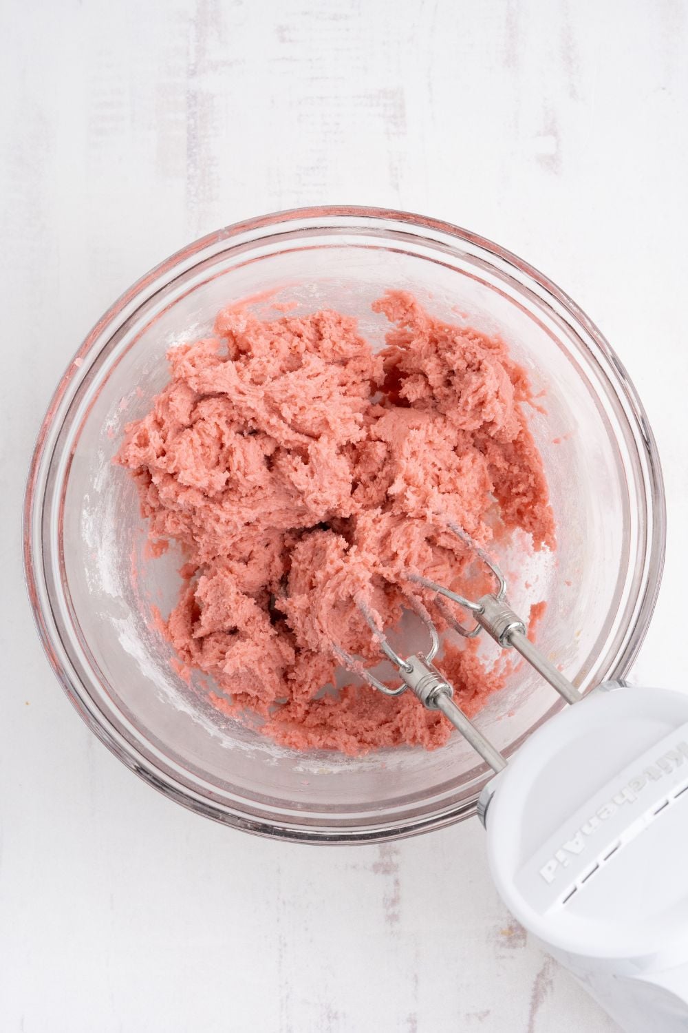 Cherry Chocolate Chip Cookie dough that is colored pink and being mixed with a hand mixer 