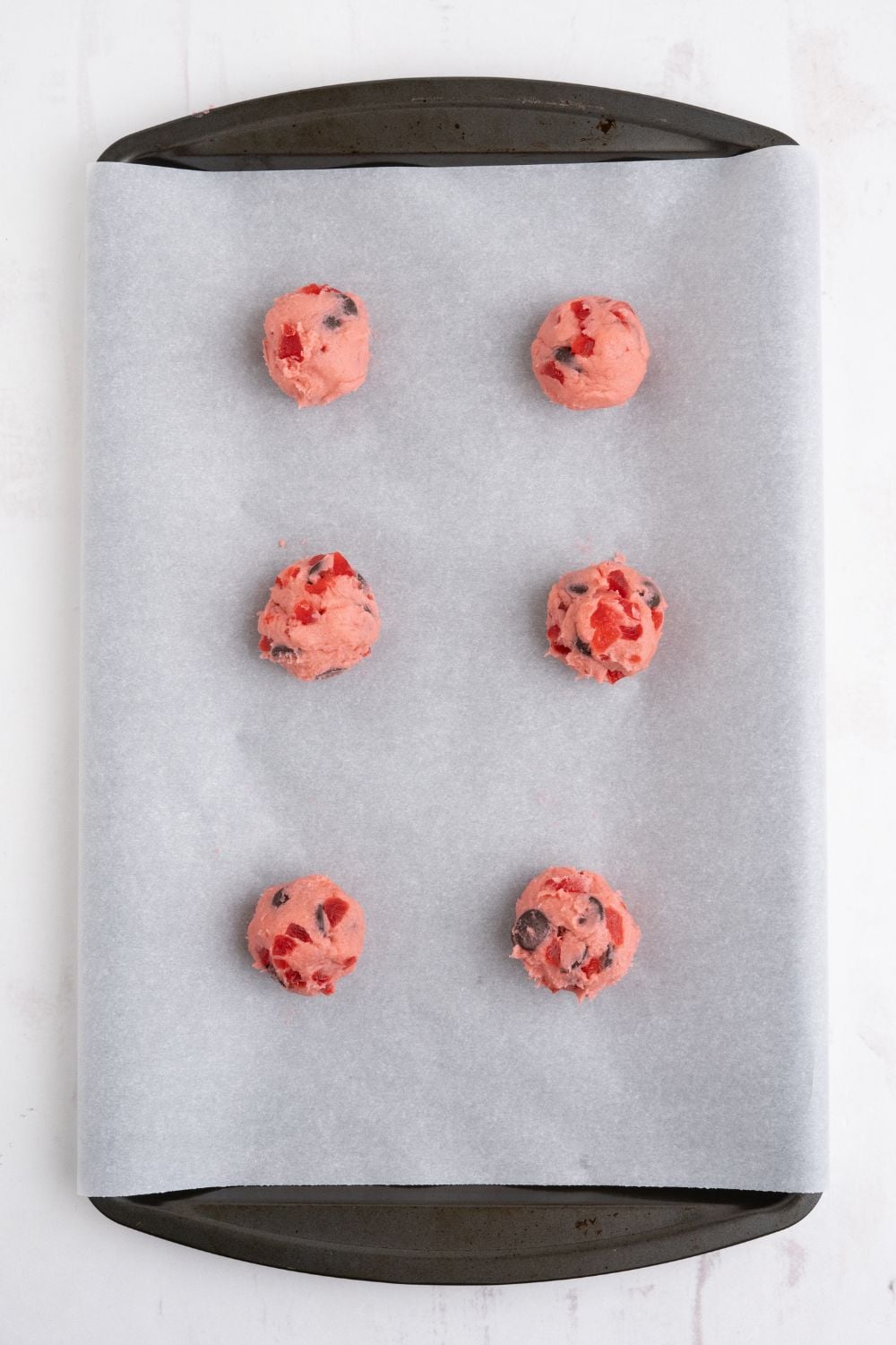 Cherry Chocolate Chip Cookie dough balls on a parchment lined pan 