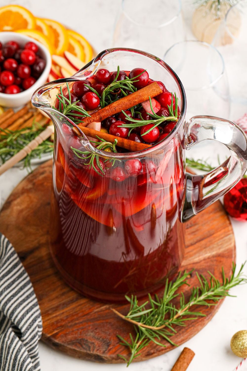 pitcher of sangria topped with cranberries, herbs and cinnamon sticks