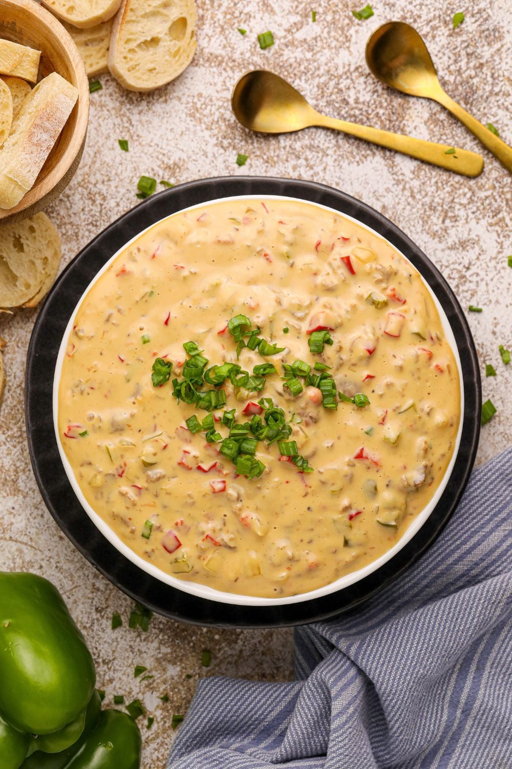 Crock Pot Philly Cheesesteak Dip in a black bowl with sliced bread and a towel around the bowl on counter
