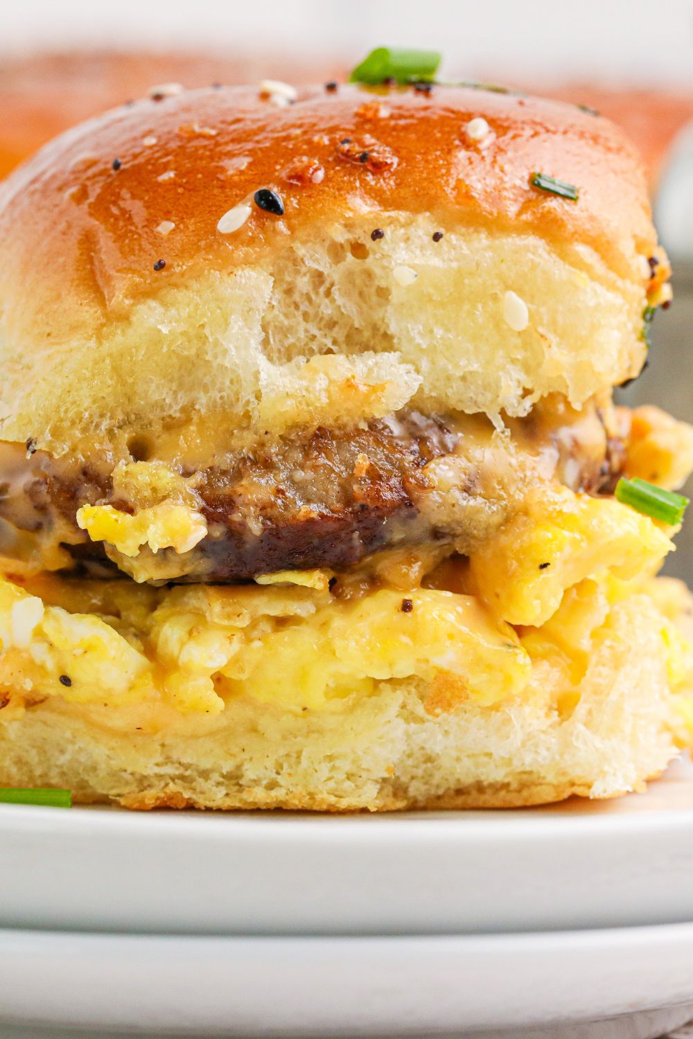 Breakfast Slider on plate with a close up view of the sausage and eggs in the sandwich 