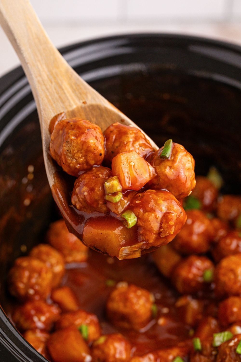 Slow Cooker 3 Ingredient Hawaiian Meatballs in a slow cooker with a spatula with a few meatballs on 