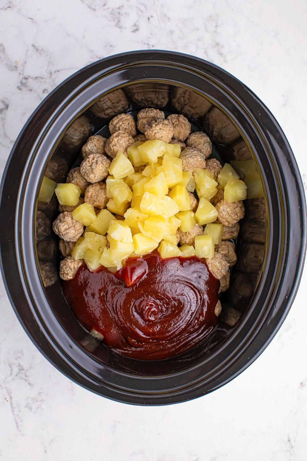 Slow Cooker 3 Ingredient Hawaiian Meatballs in a crockpot with pineapple, sauce, and meatballs inside 