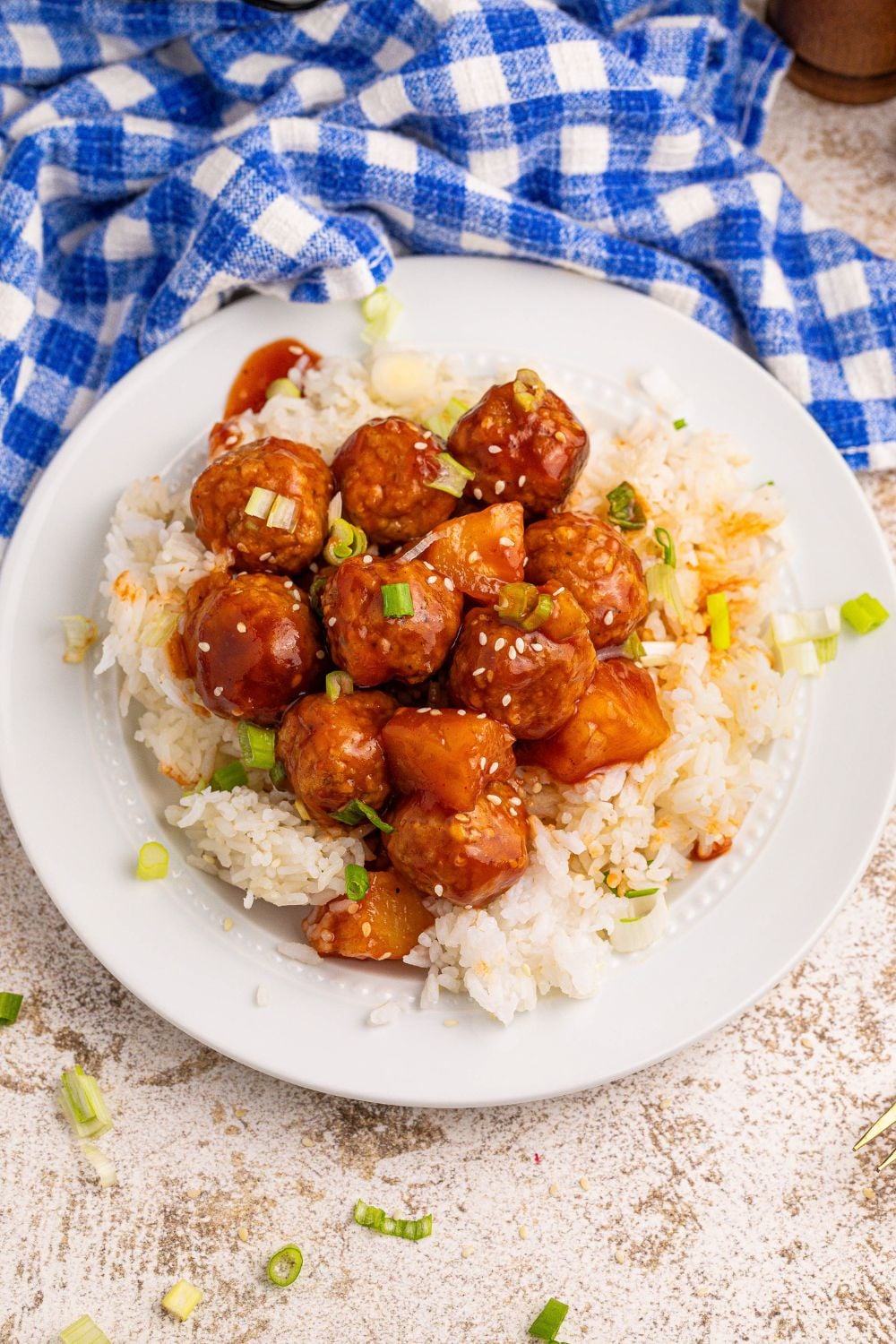 Slow Cooker 3 Ingredient Hawaiian Meatballs on a white plate with white rice and sesame seeds on the top of meatballs 