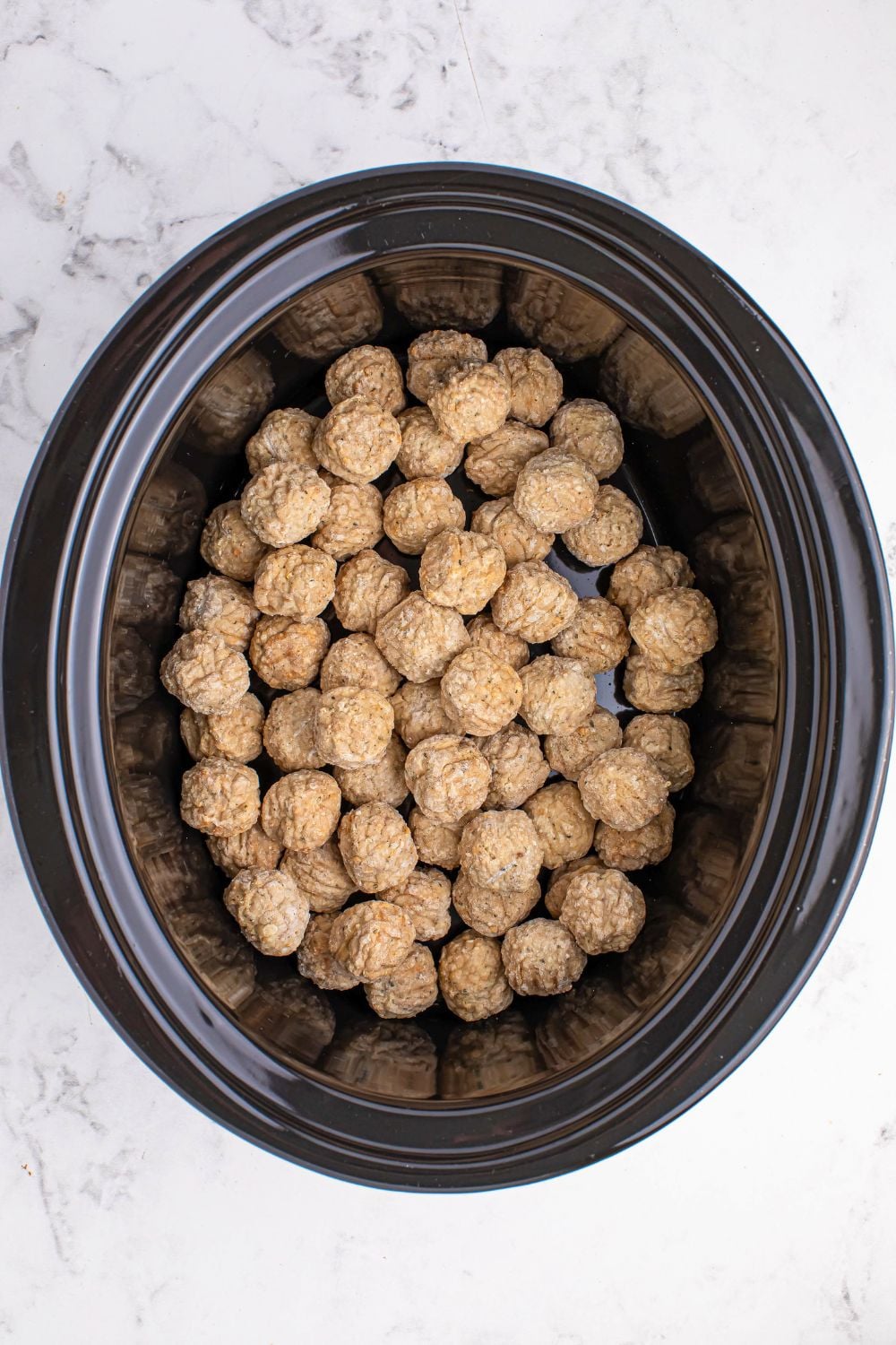 frozen meatballs in a slow cooker on the table 