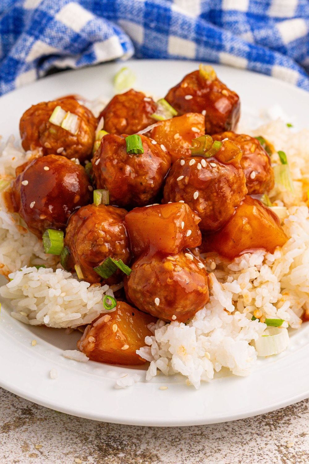 Slow Cooker 3 Ingredient Hawaiian Meatballs on a plate topped iwth sesame seeds and green onions 