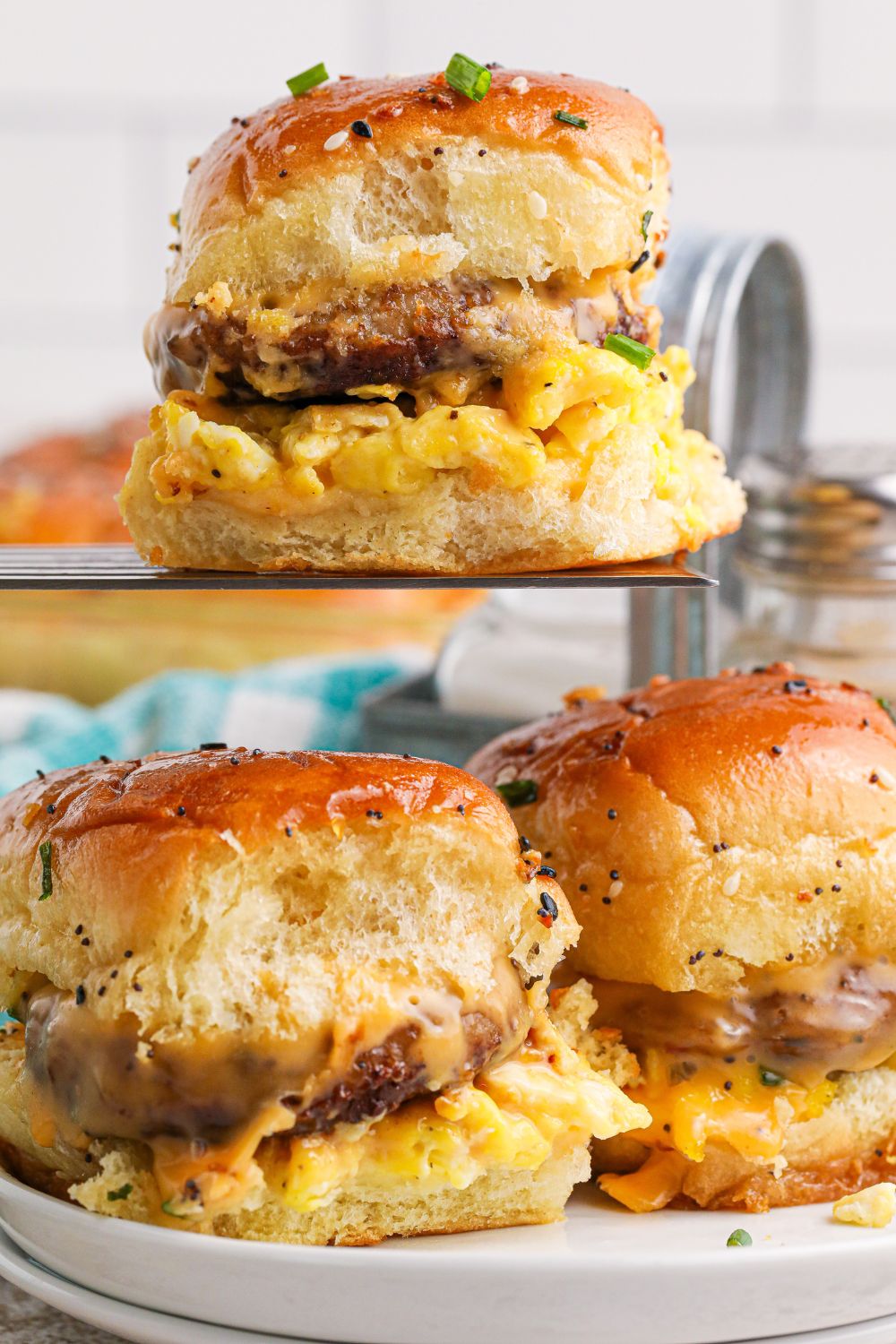 Breakfast Sliders on a plate with one on a spatula above plate 