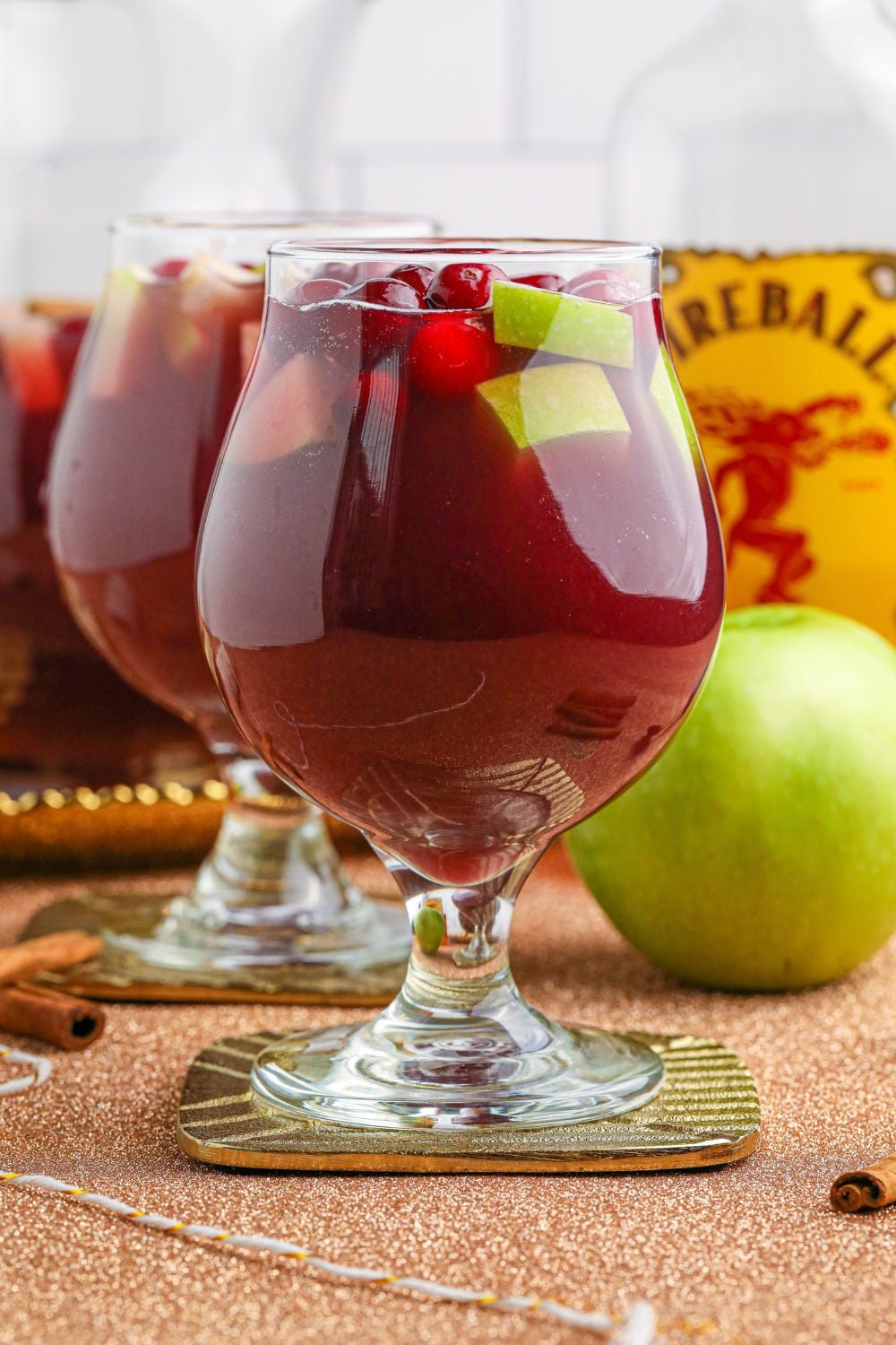 side view of glasses on table with apple and fireball behind glasses