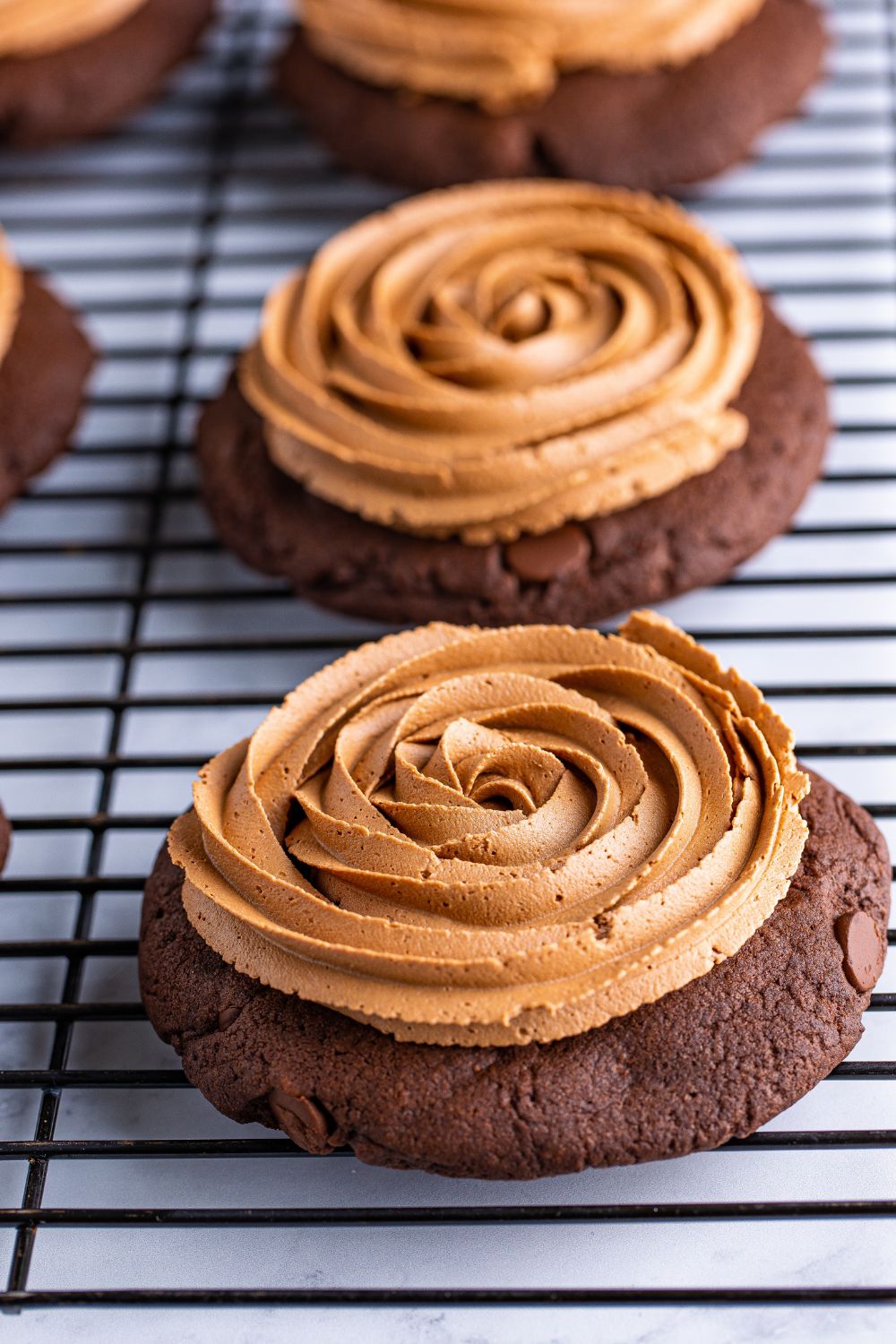 Chocolate Cake Cookies on a cooling rack topped with frosting 