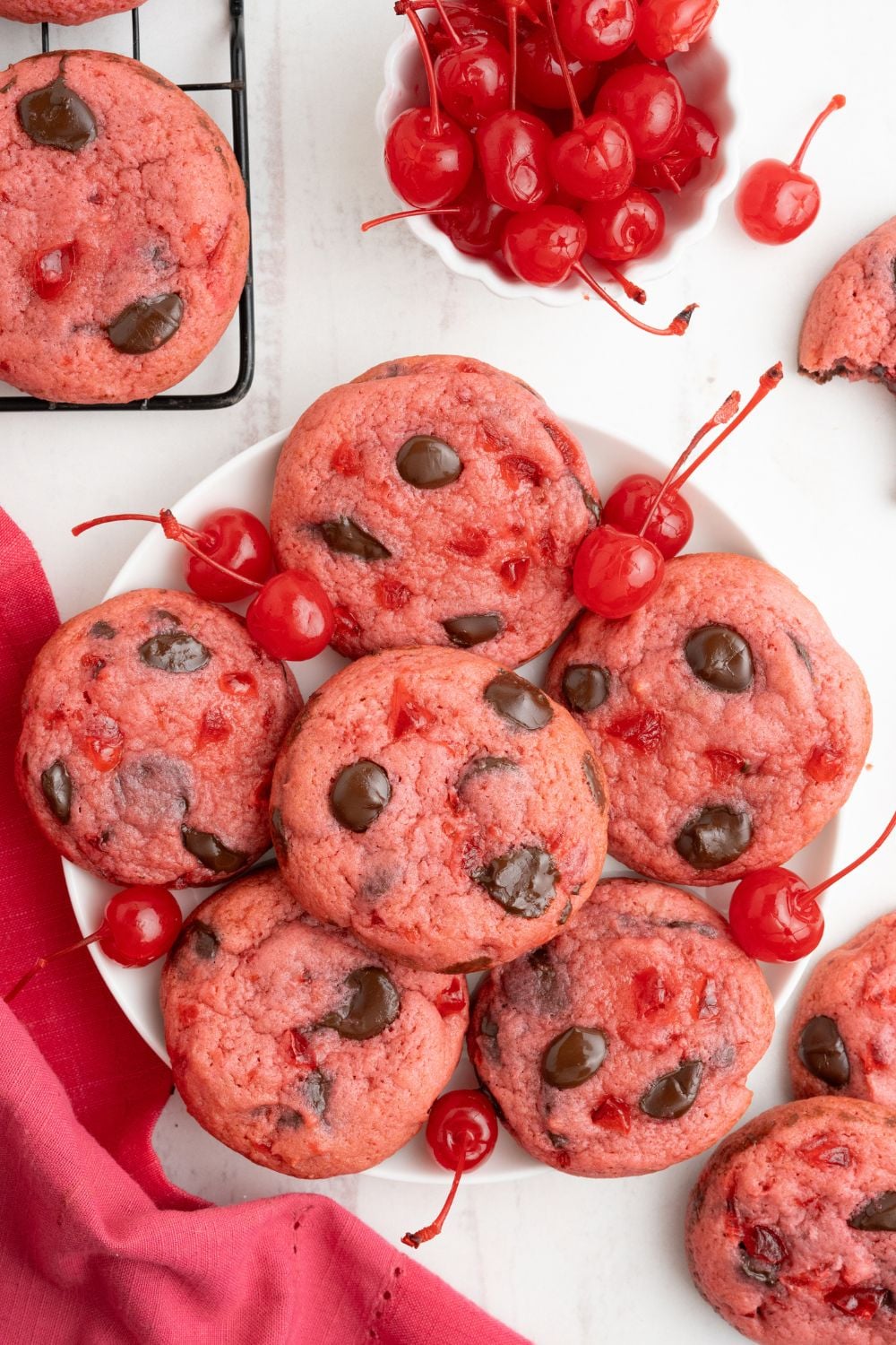 overhead look of Cherry Chocolate Chip Cookies on a plate with cherries placed around the cookies 