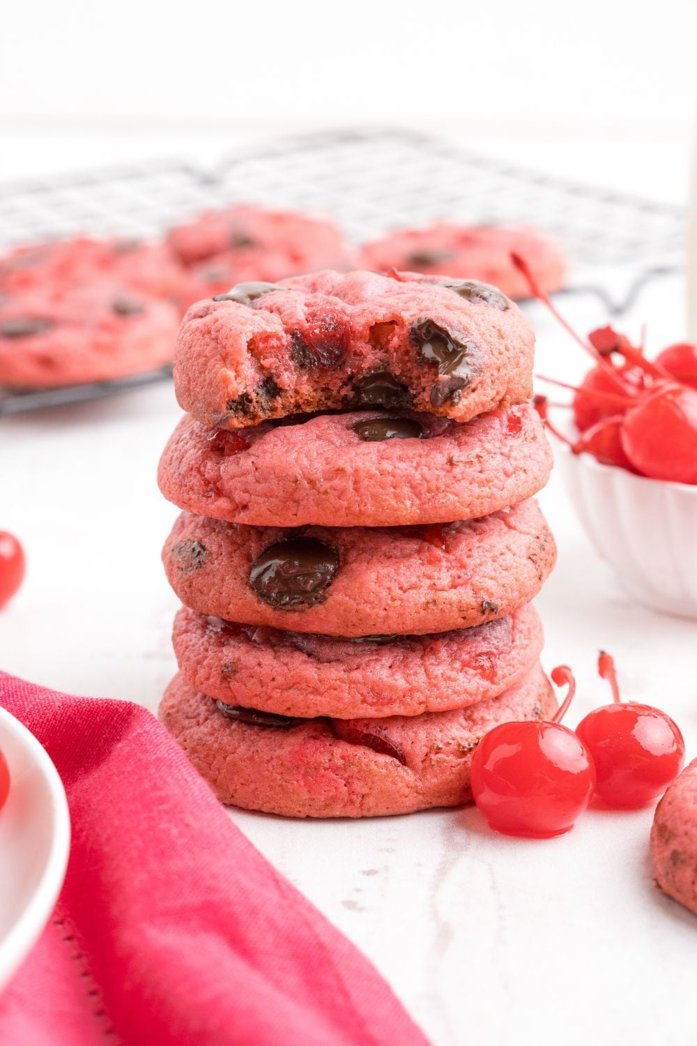 Cherry Chocolate Chip Cookies stacked on table with one bite taken out of the cookie 