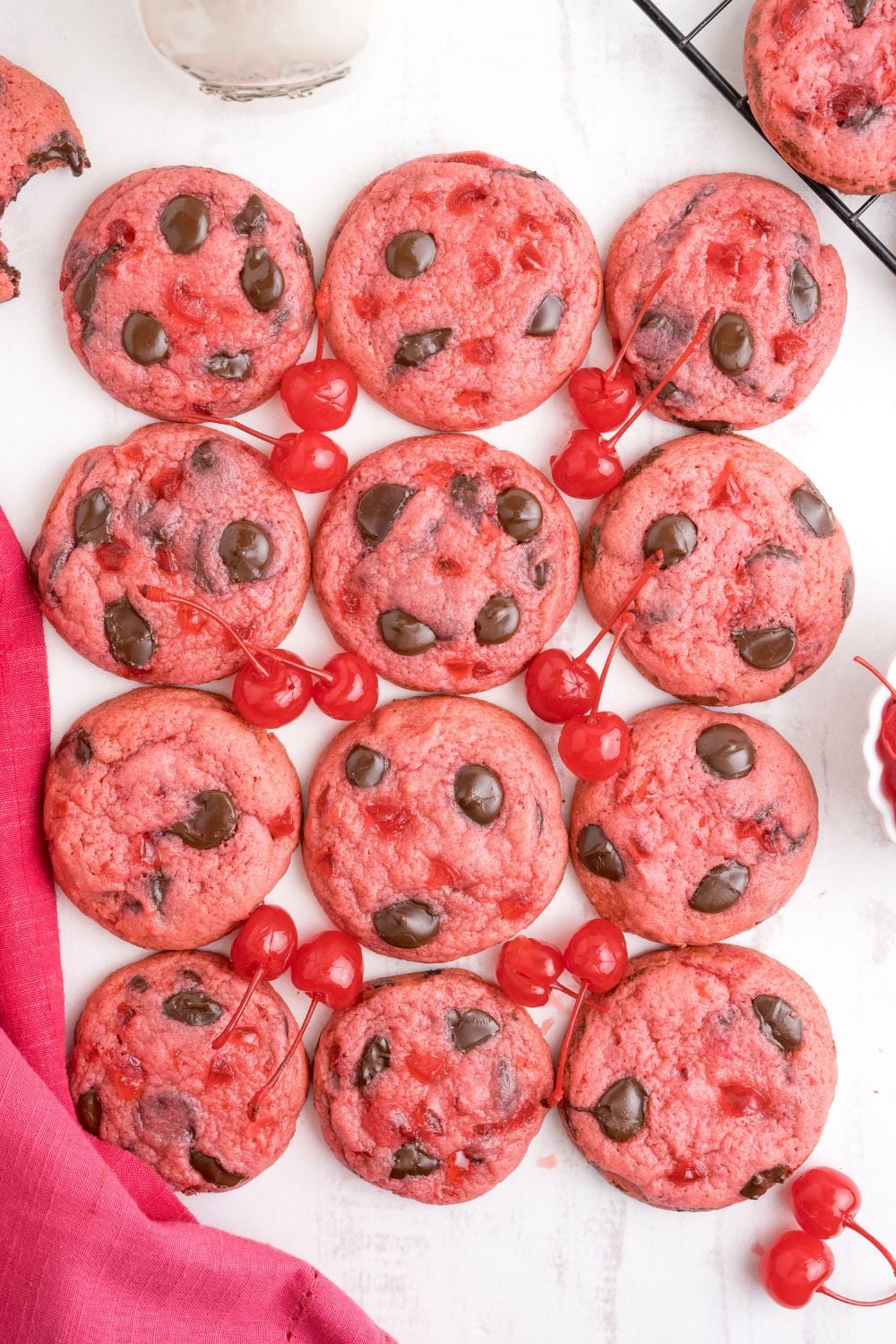 Cherry Chocolate Chip Cookies placed on the table with a towel and real cherries on the side 