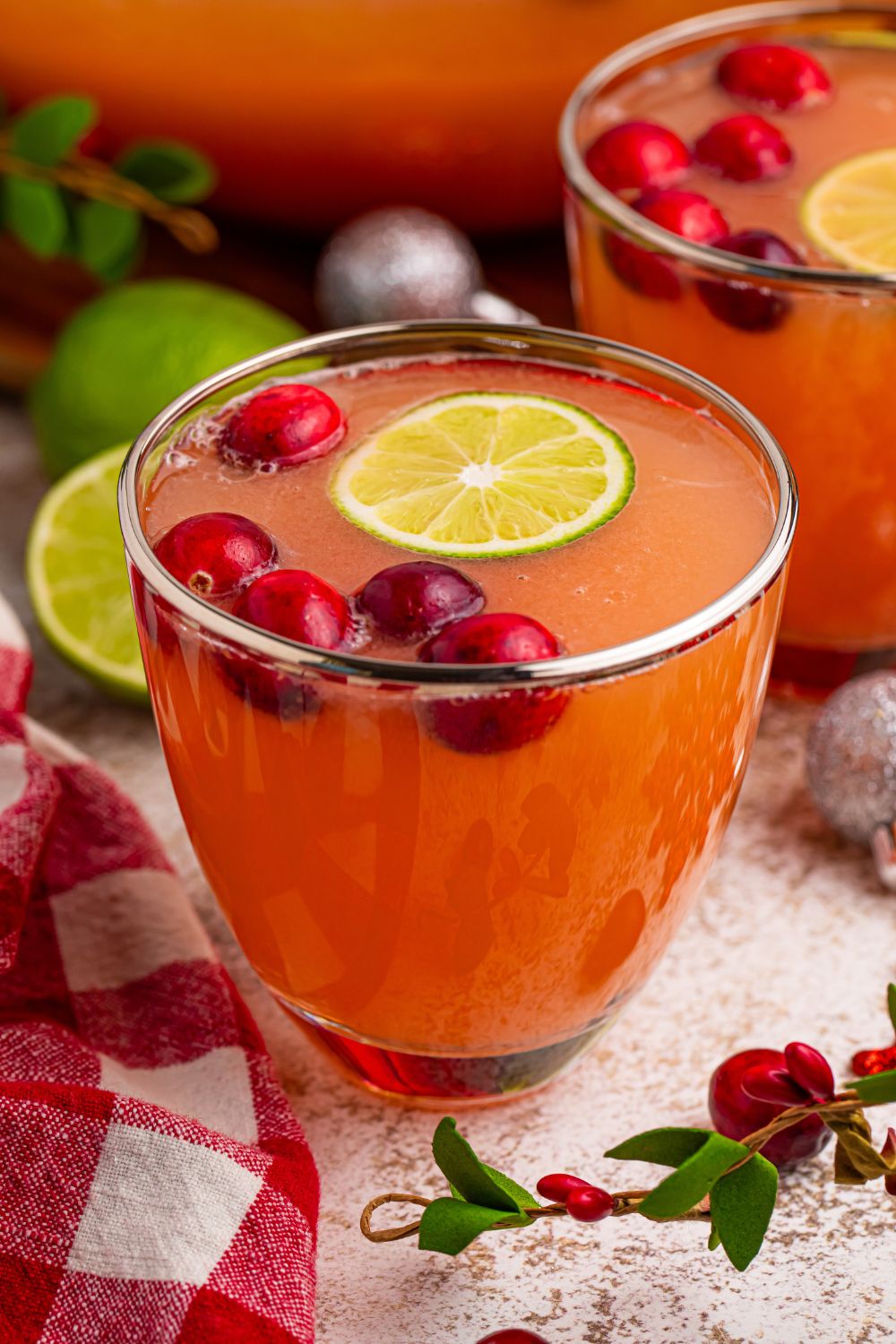 punch in glasses on table with cranberry and lime garnish
