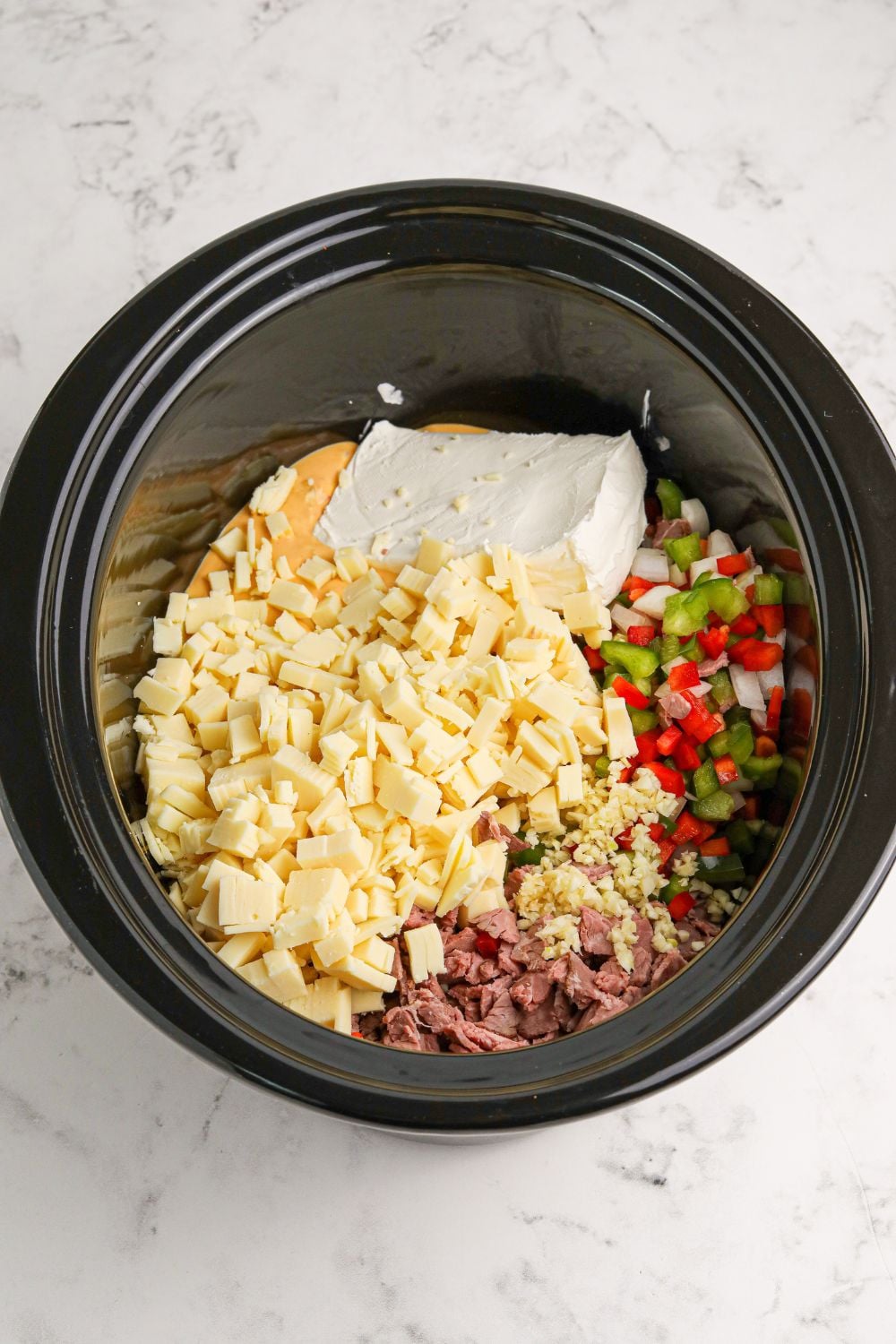 Crock Pot Philly Cheesesteak Dip ingredients in the slow cooker above the pan