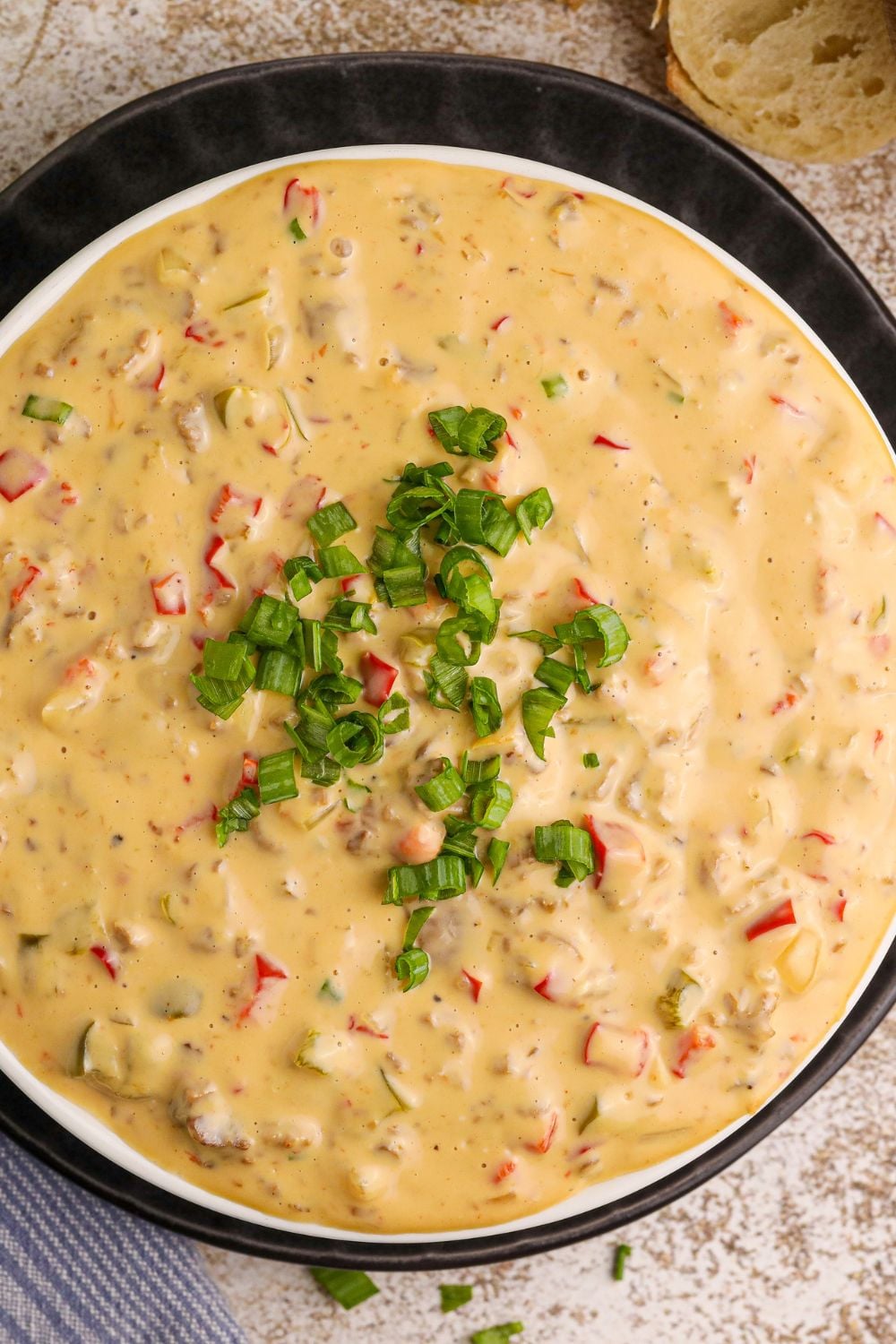 Crock Pot Philly Cheesesteak Dip in a black bowl with some green garnish on top of it