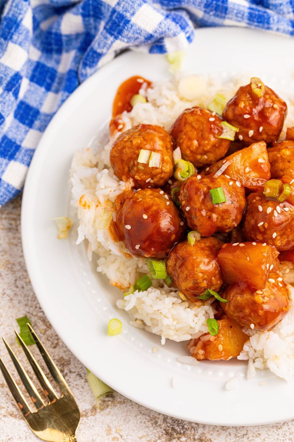 Slow Cooker 3 Ingredient Hawaiian Meatballs on plate with a fork and blue napkin placed on side of plate 