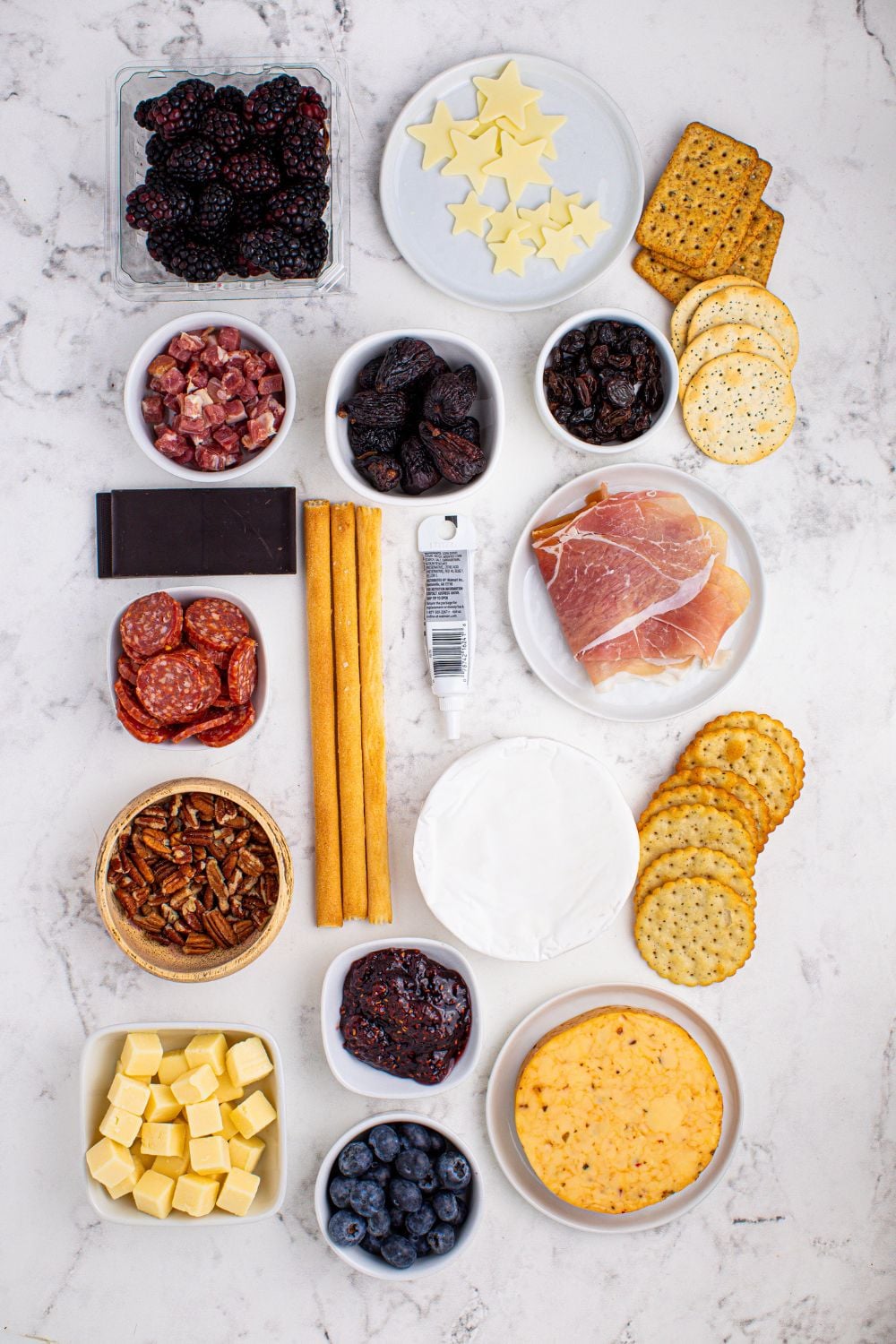 New Year's Eve Charcuterie Board ingredients placed on the table in glass bowls to showcase each item for the charcuterie snacking board 