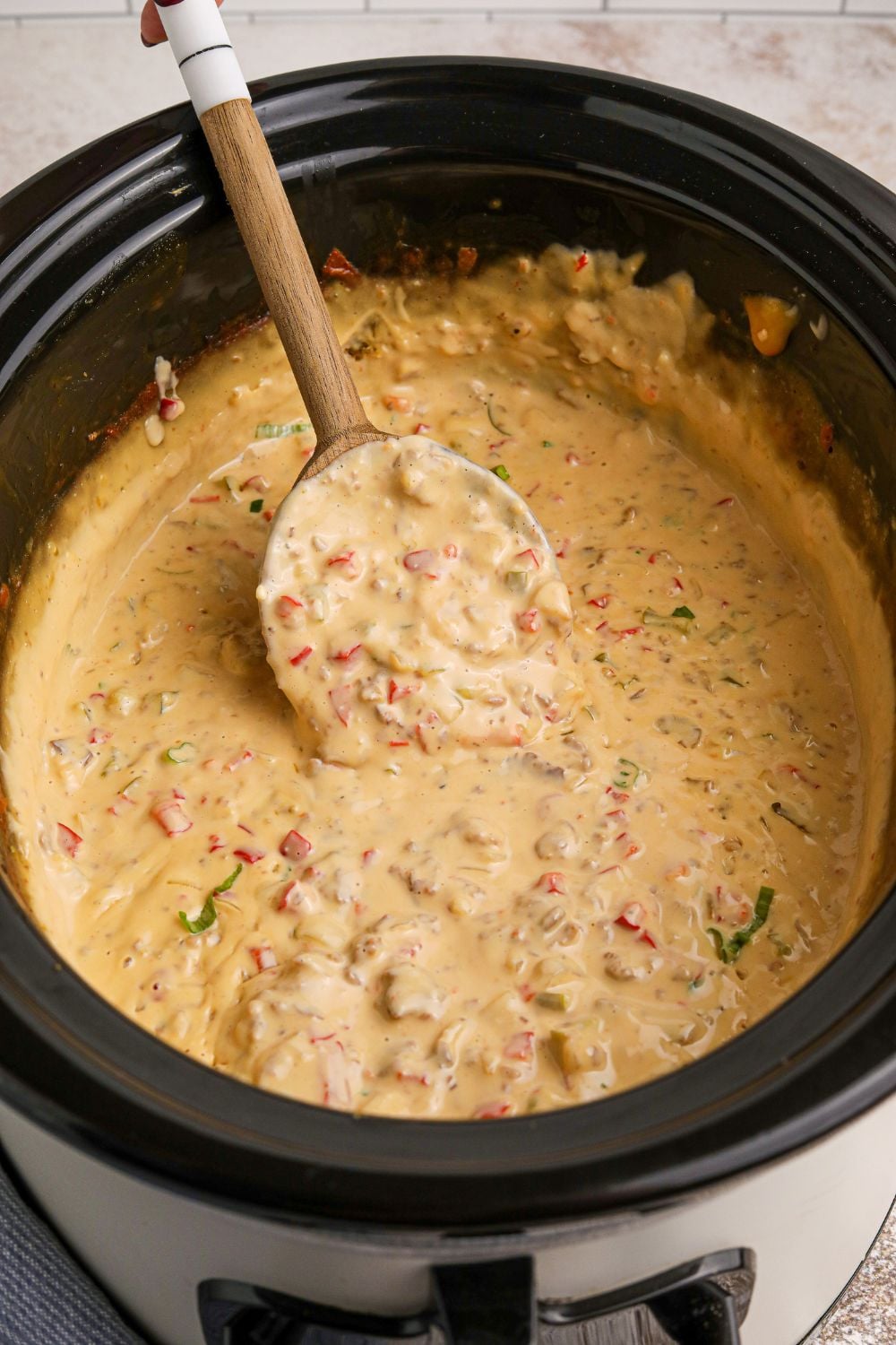 Crock Pot Philly Cheesesteak Dip in a slow cooker with a wooden spoon in the crockpot