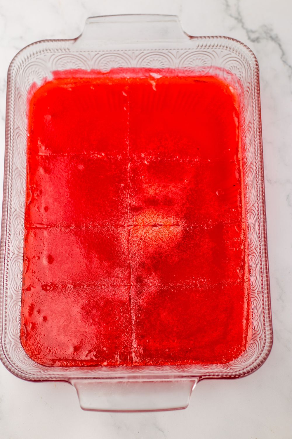 red jello in a pan cut into squares 