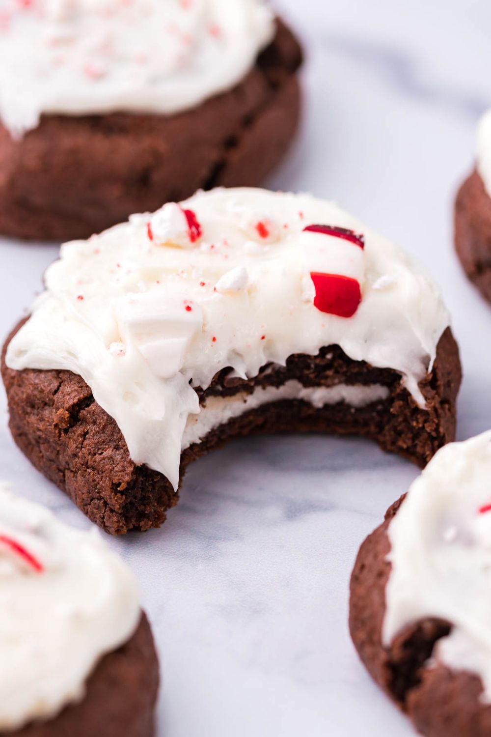 peppermint patty cookie with bite taken out sitting on a marble table with cookies around it 