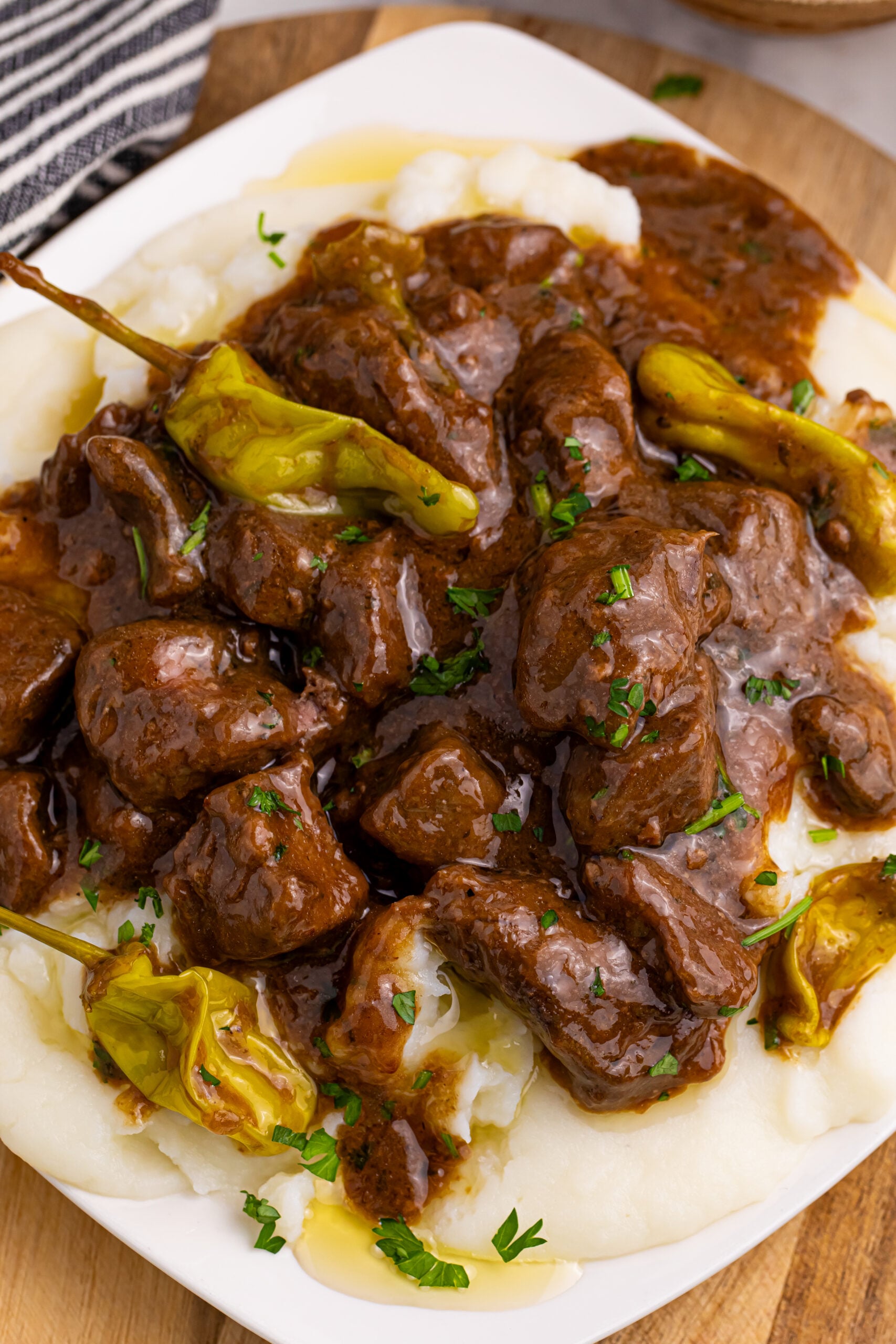 Crockpot Mississippi Steak Bites over a bed of mashed potatoes on plate sitting on table