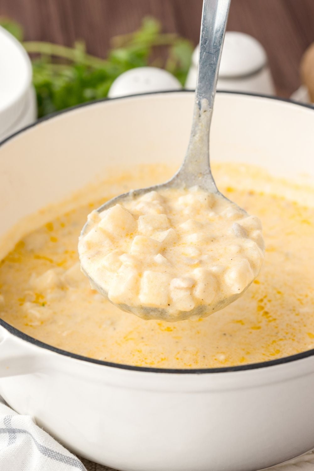 Hash Brown Potato Soup in a white pot with a ladle full of soup in the center of the pot