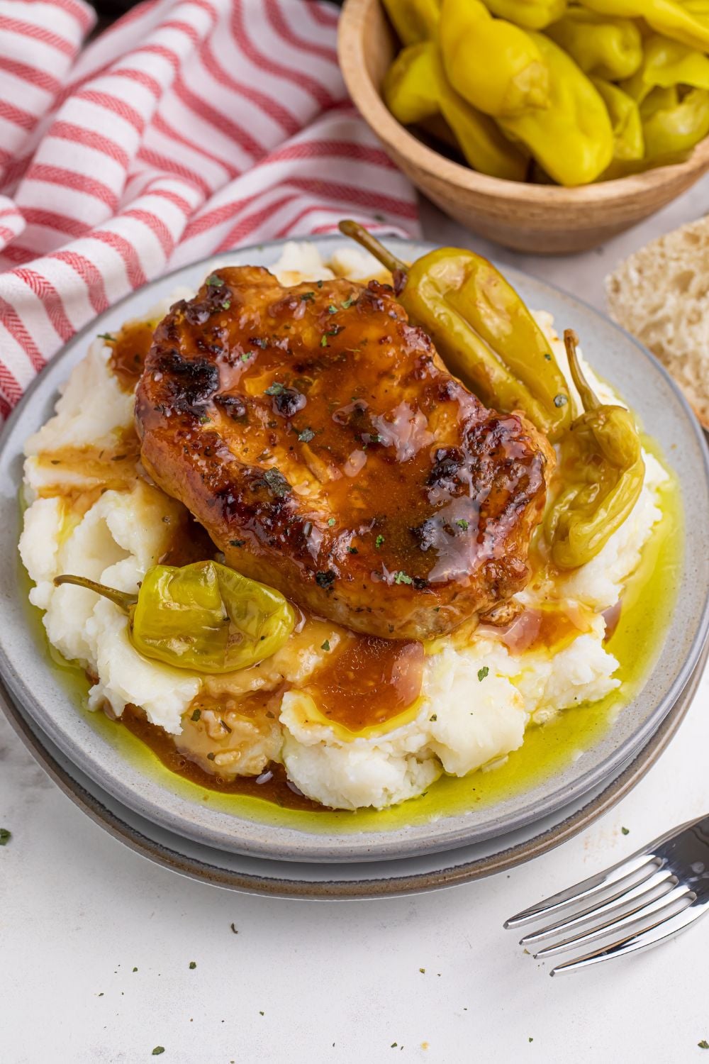 Crock Pot Mississippi Pork Chops on a plate with pork chop, mashed potatoes, and peppers