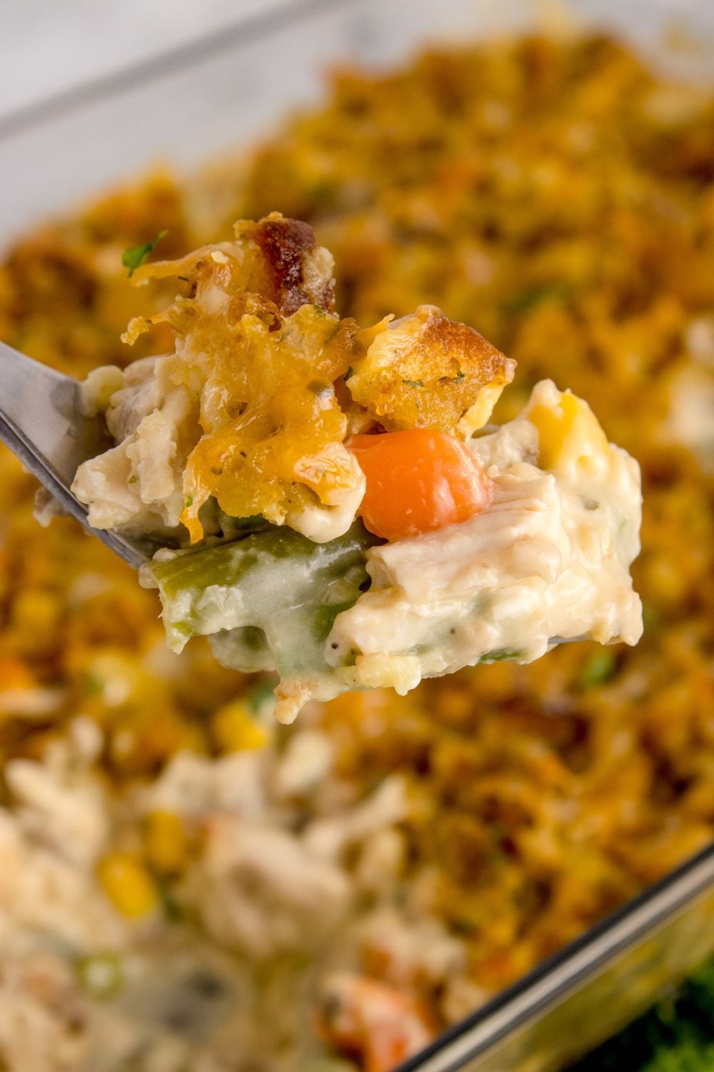 Chicken Stuffing Casserole in pan with a metal pan scooping out the mixture
