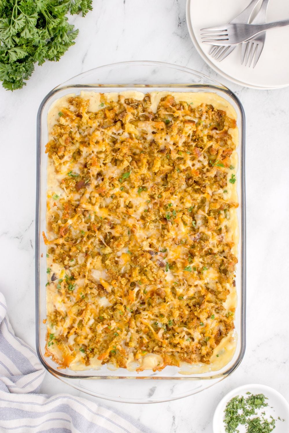 Chicken Stuffing Casserole on table in a glass casserole dish with fresh parsely around the pan on table